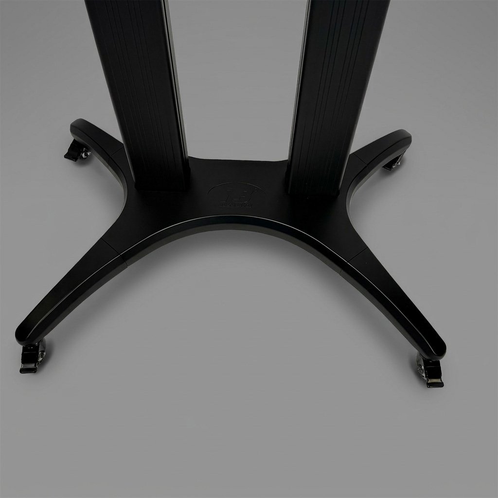 Close-up view of the base of a black adjustable-height standing desk, with four caster wheels on a gray surface.