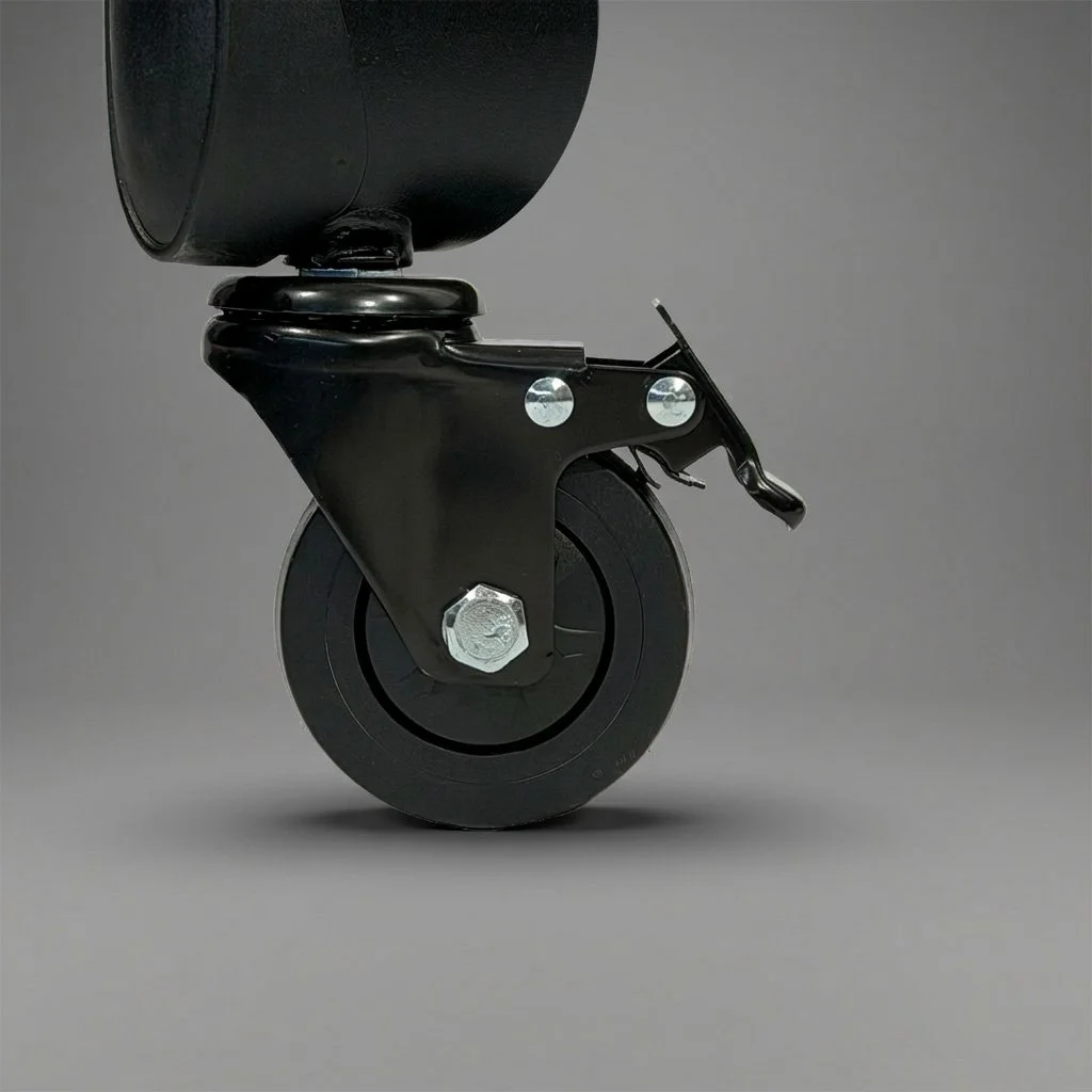 Close-up of a black caster wheel attached to furniture or equipment, mounted with metal bolts and a brake lever.