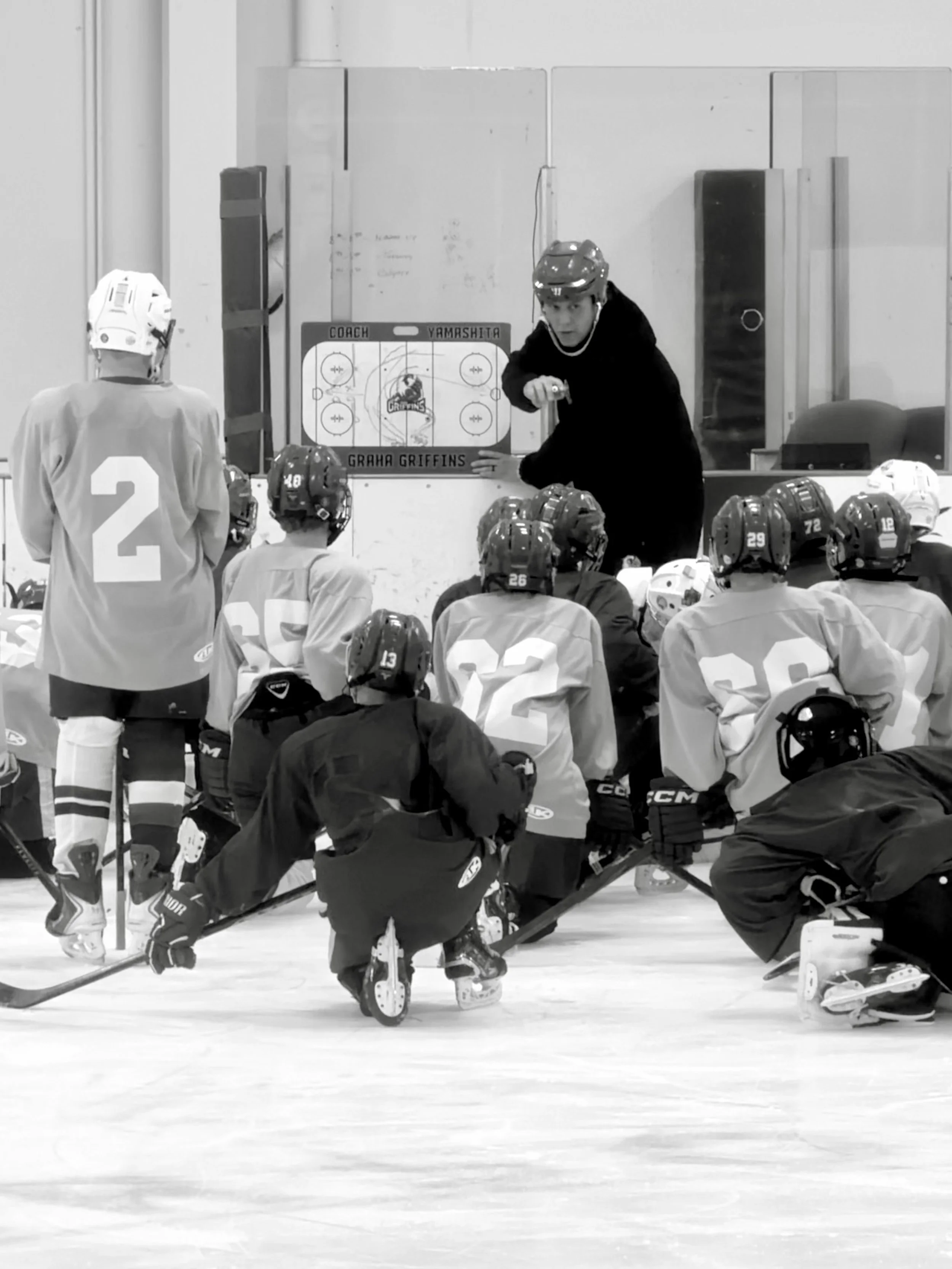 Hockey coach instructs players during practice on Ice rink.