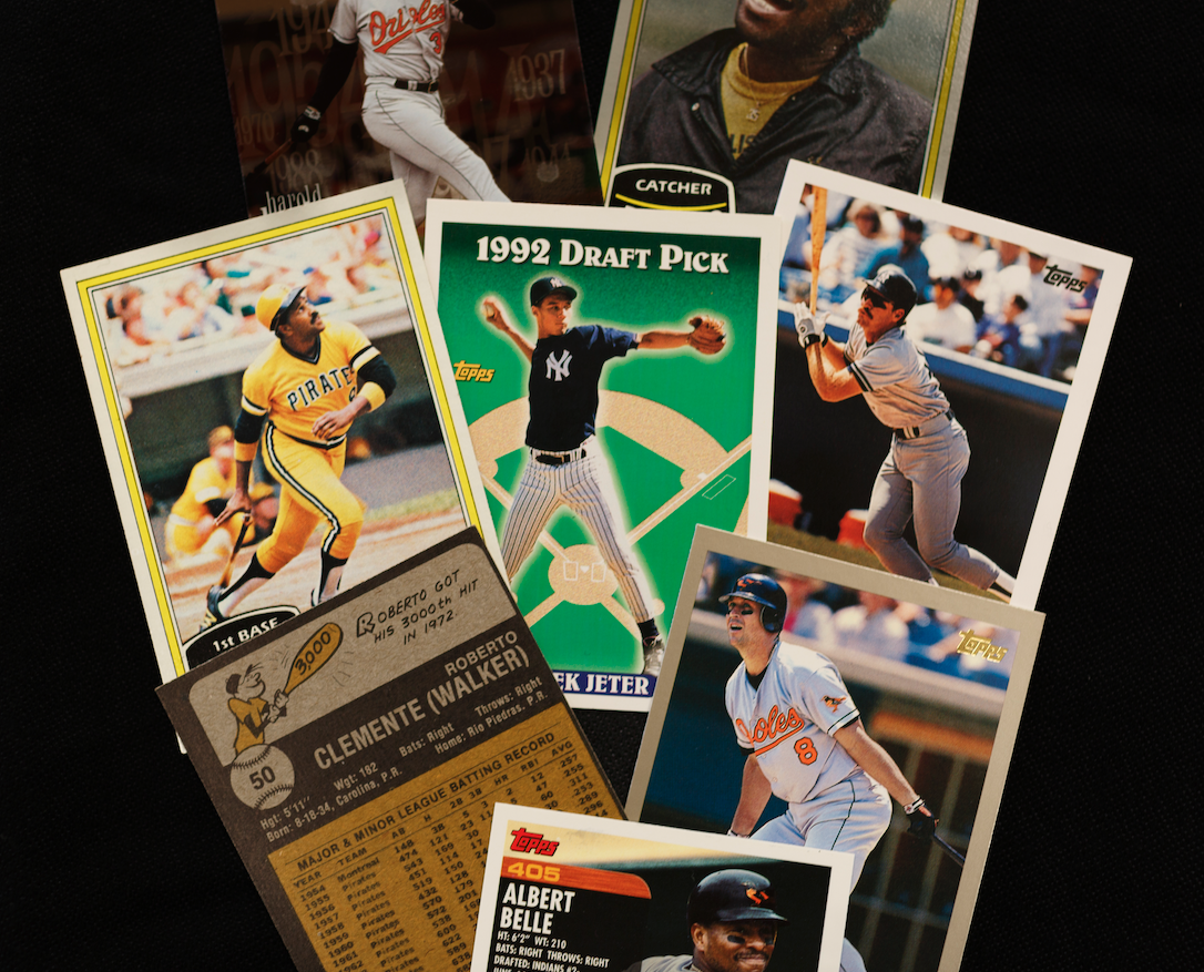 A collection of vintage baseball cards, including a 1992 Topps draft pick card of a young pitcher, a card of a player in a yellow Pirates uniform, a player in a gray Yankees uniform, a player in an Orioles uniform, and two other baseball cards, one featuring a catcher and another showing a player in a batting stance.
