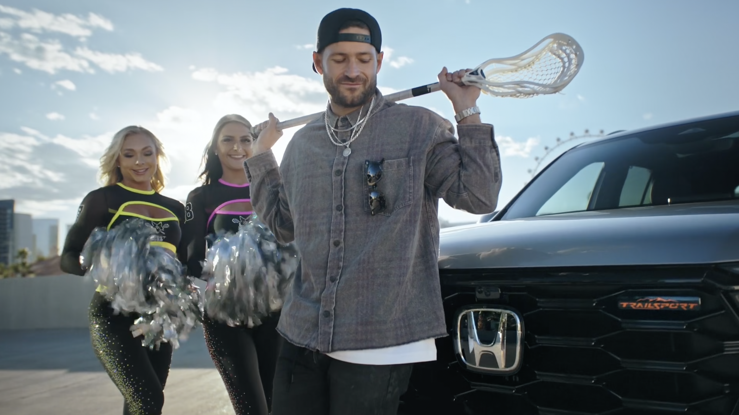 Professional lacrosse player and cheerleaders standing in front of Honda SUV.