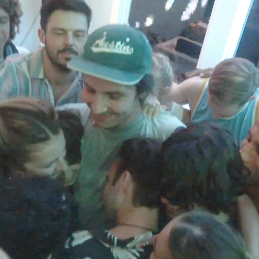A group of people gathered closely together, smiling and engaging with each other.