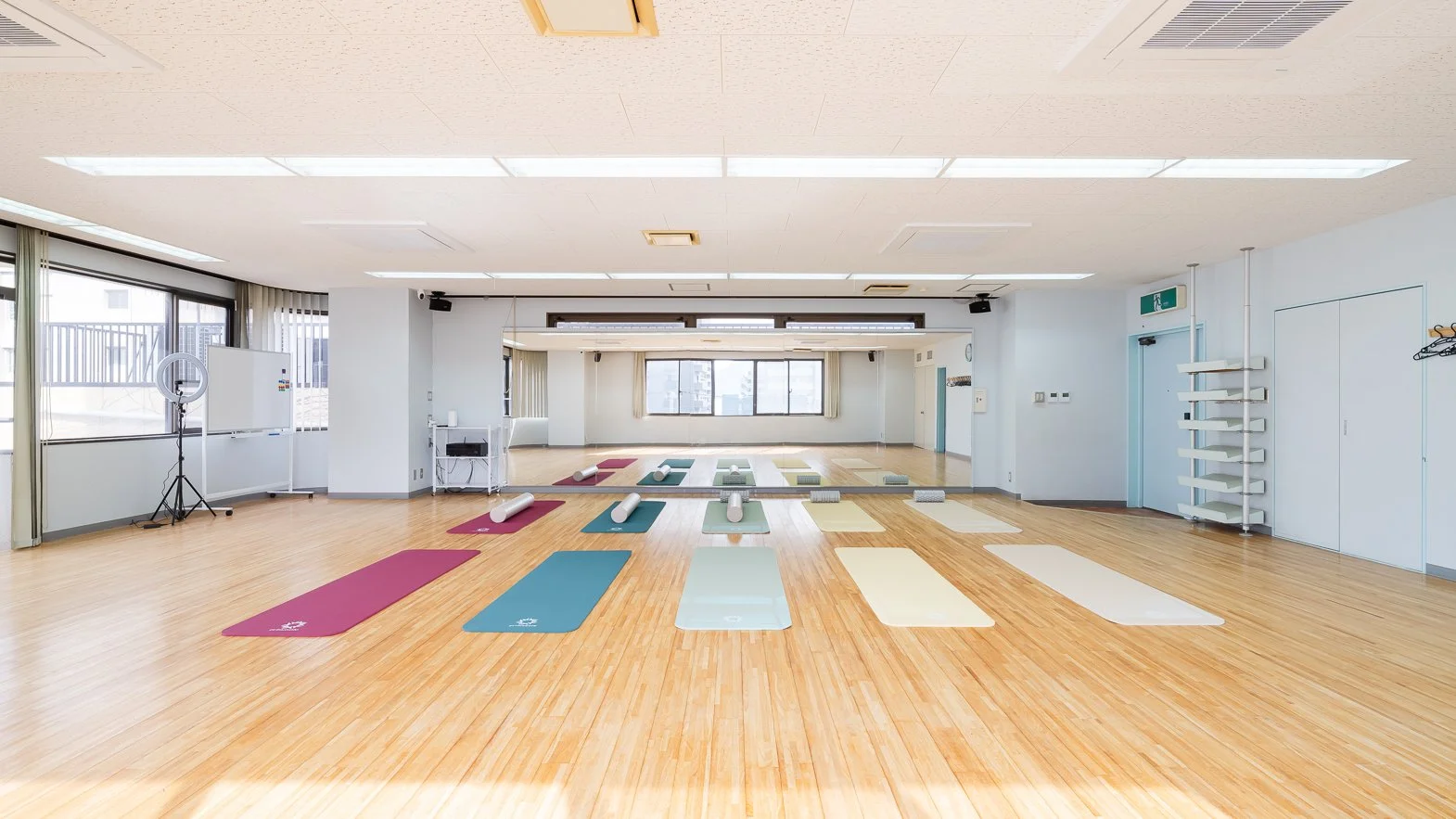 Empty yoga or fitness studio with mats, rollers, and mirrors on the wall