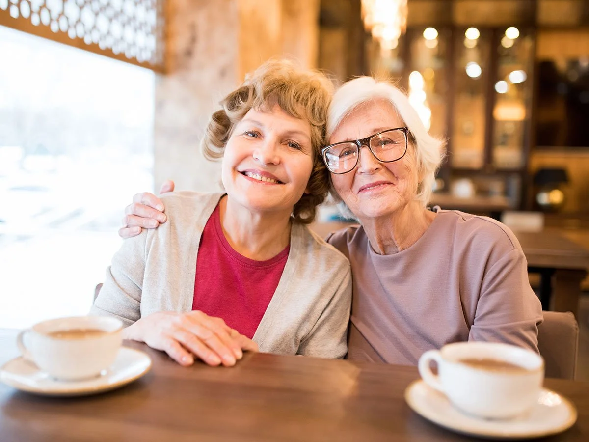 Two women enjoying friendship and social connection at the Tide & Times dementia friendly café.