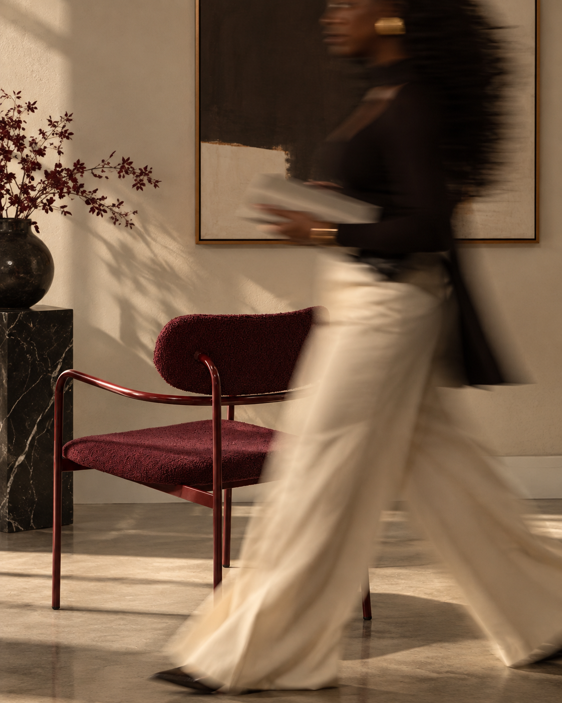 A woman walks past a framed artwork in a warm, sunlit room, softly blurred in motion.