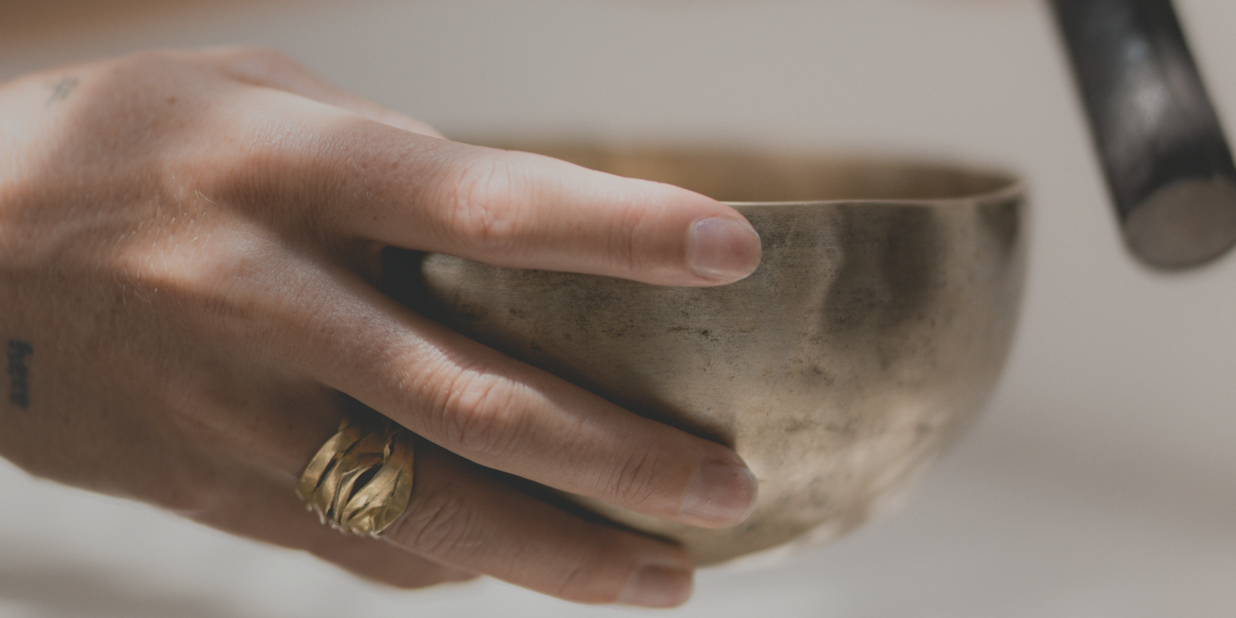 A person's hand with a ring holding a ceramic mug.