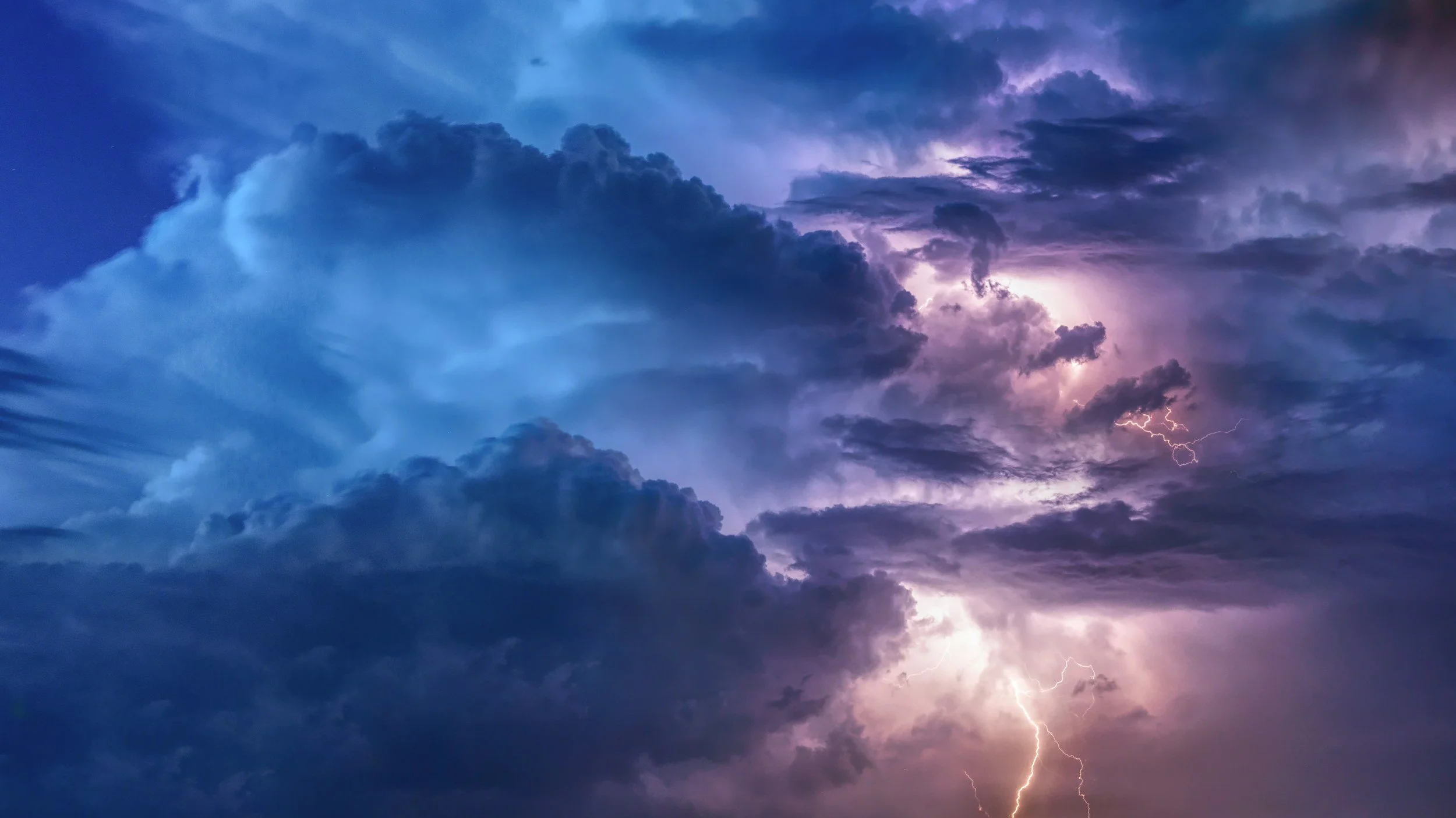 Storm clouds with lightning and purple hues in the sky.