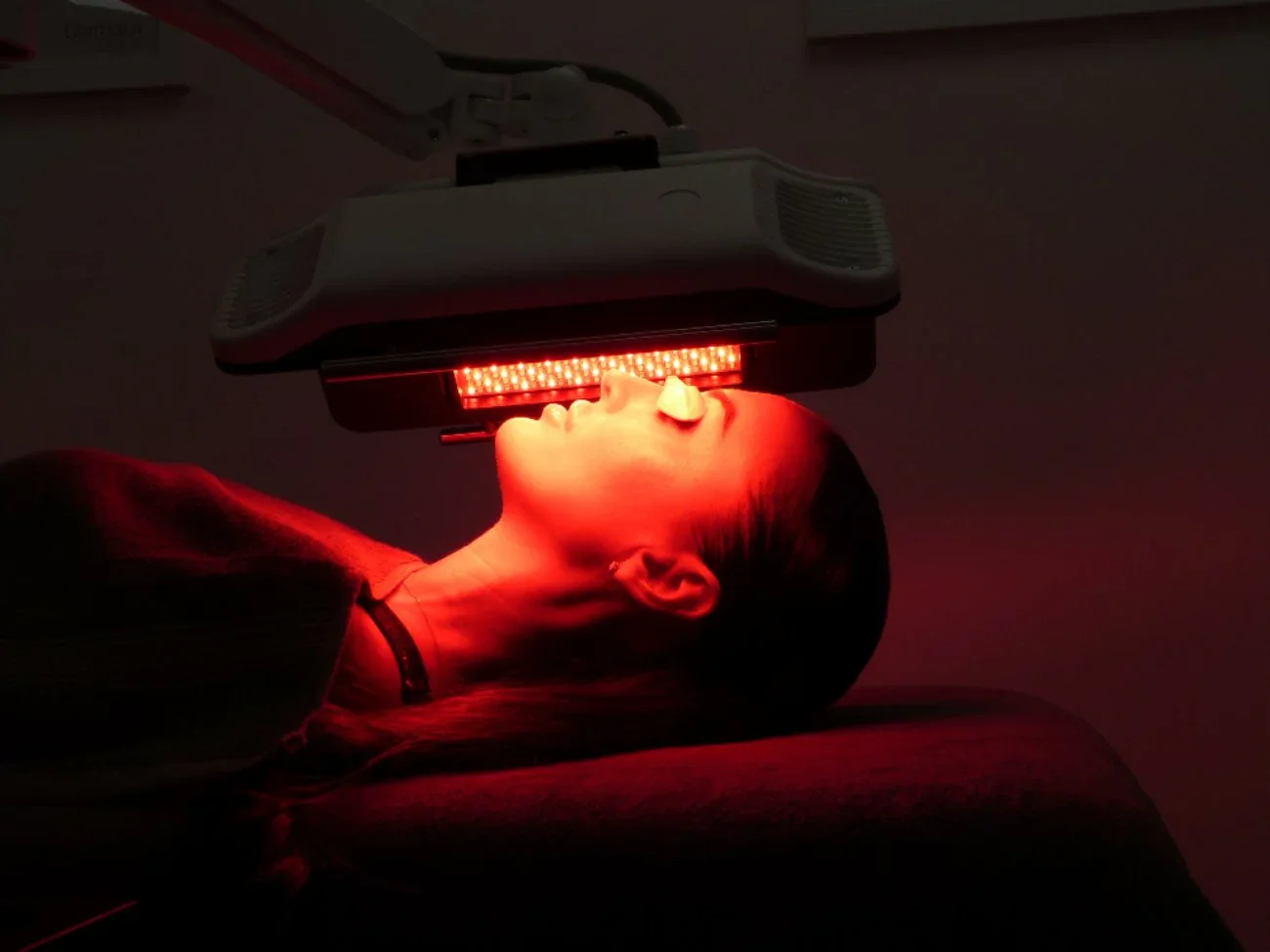 Woman lying on a treatment bed during Dermalux LED light therapy