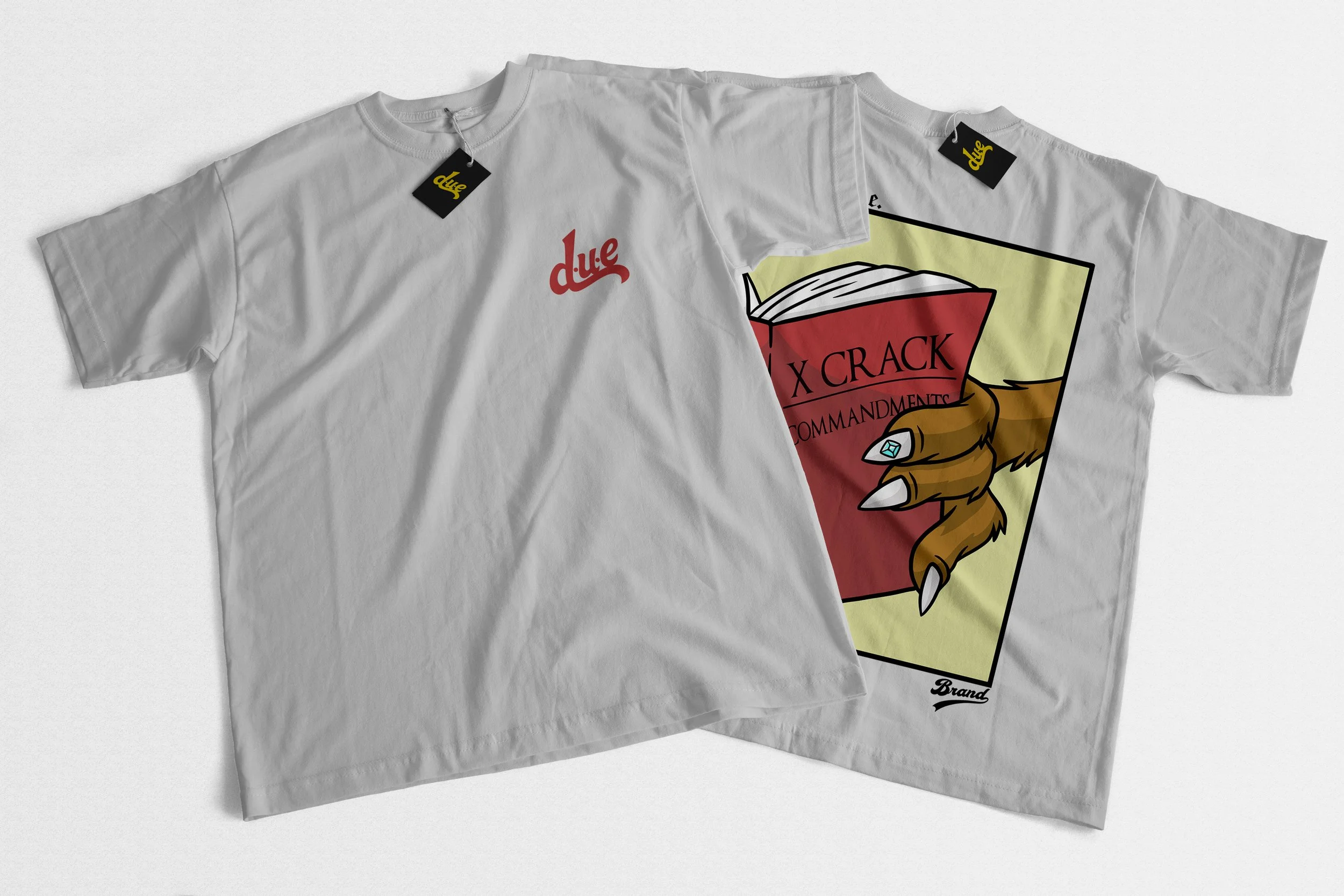 White T-shirt with a graphic of a red book titled 'X CRACK COMMANDMENTS' held in a talon with claws. The shirt has tags with yellow text that says 'due'.