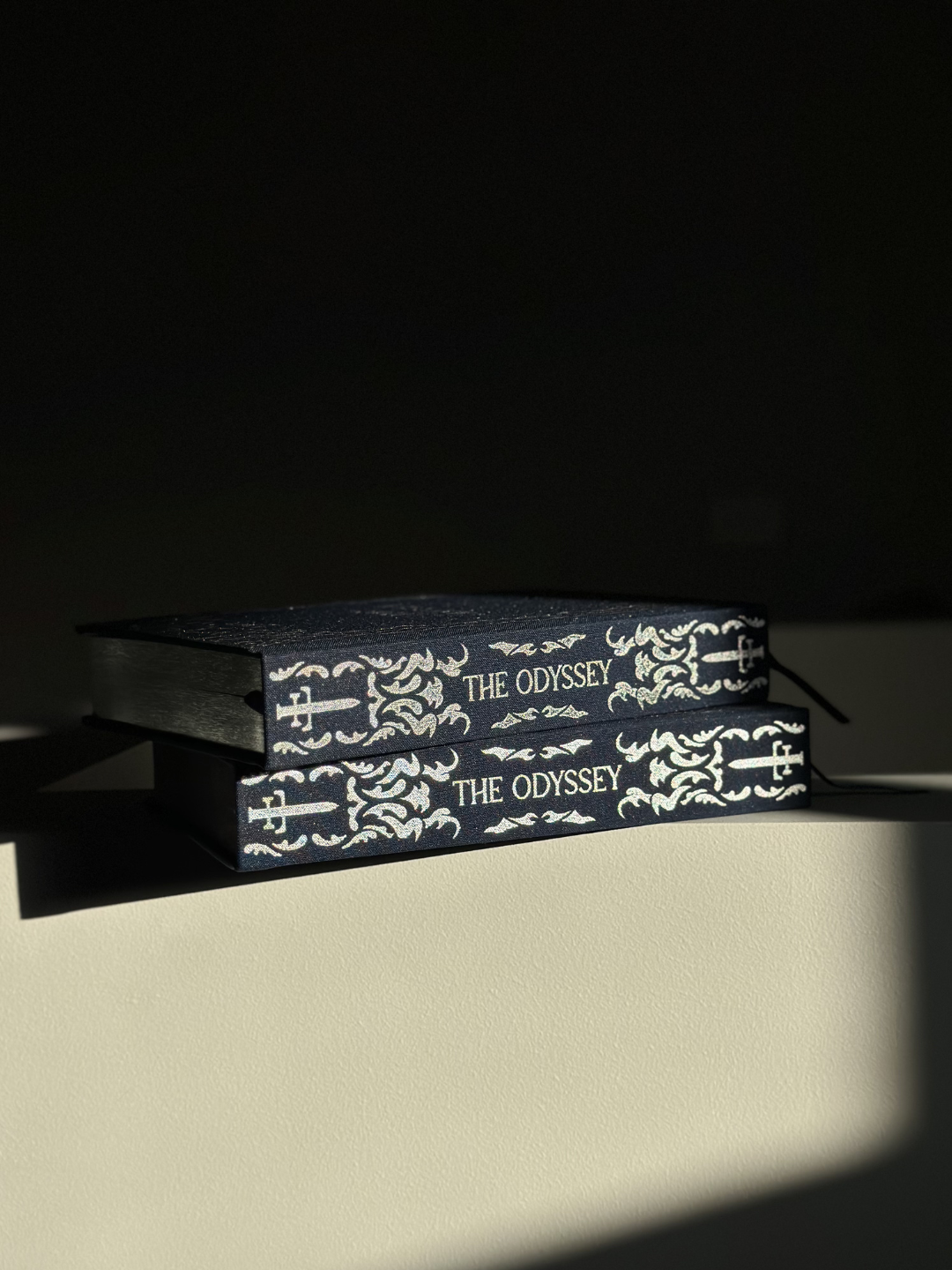 Stacked copies of The Odyssey collector’s edition showing the silver foiled page edges and decorative spine.