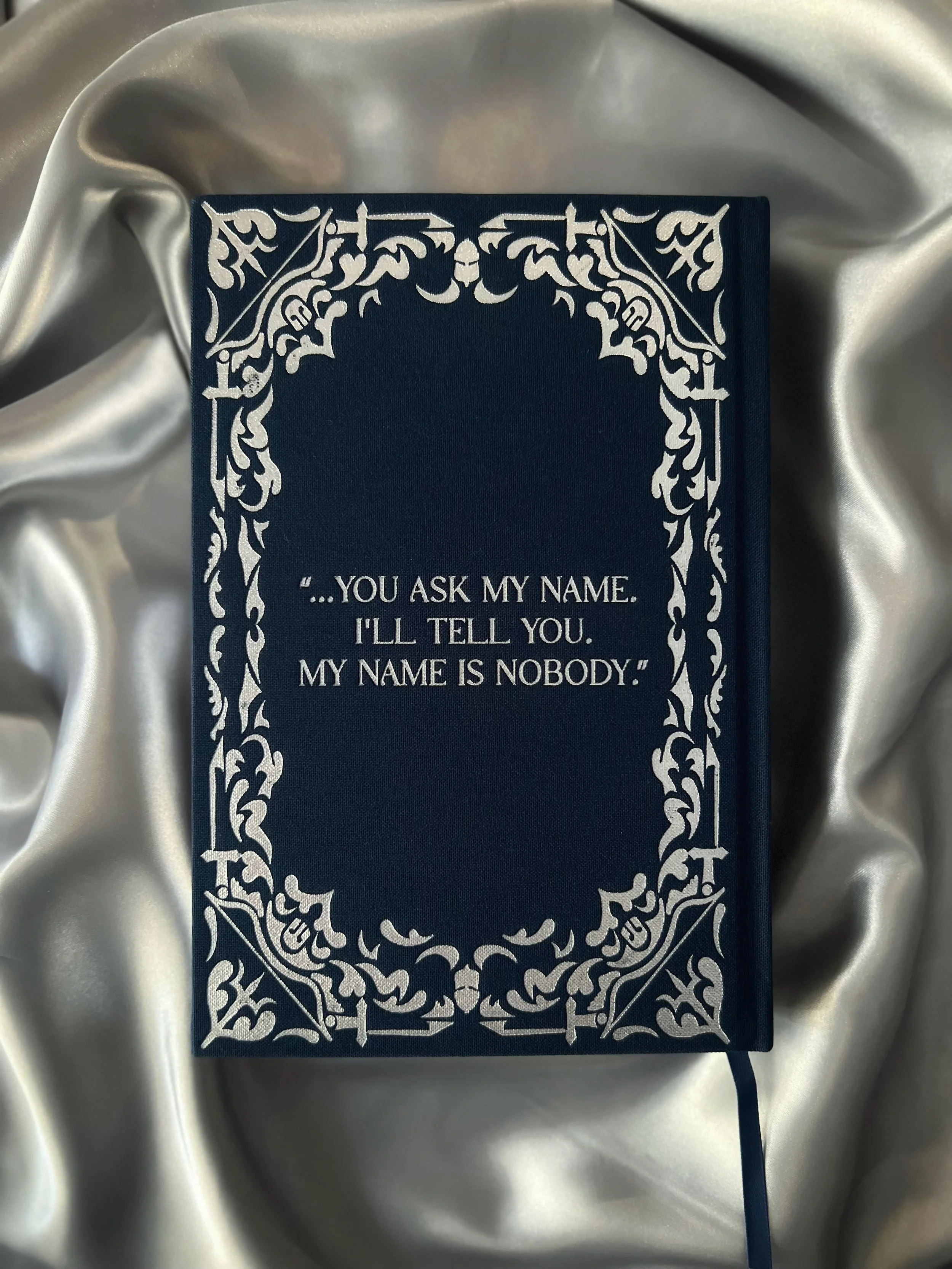 Back cover of The Odyssey collector’s edition featuring silver foil artwork and quote detailing.