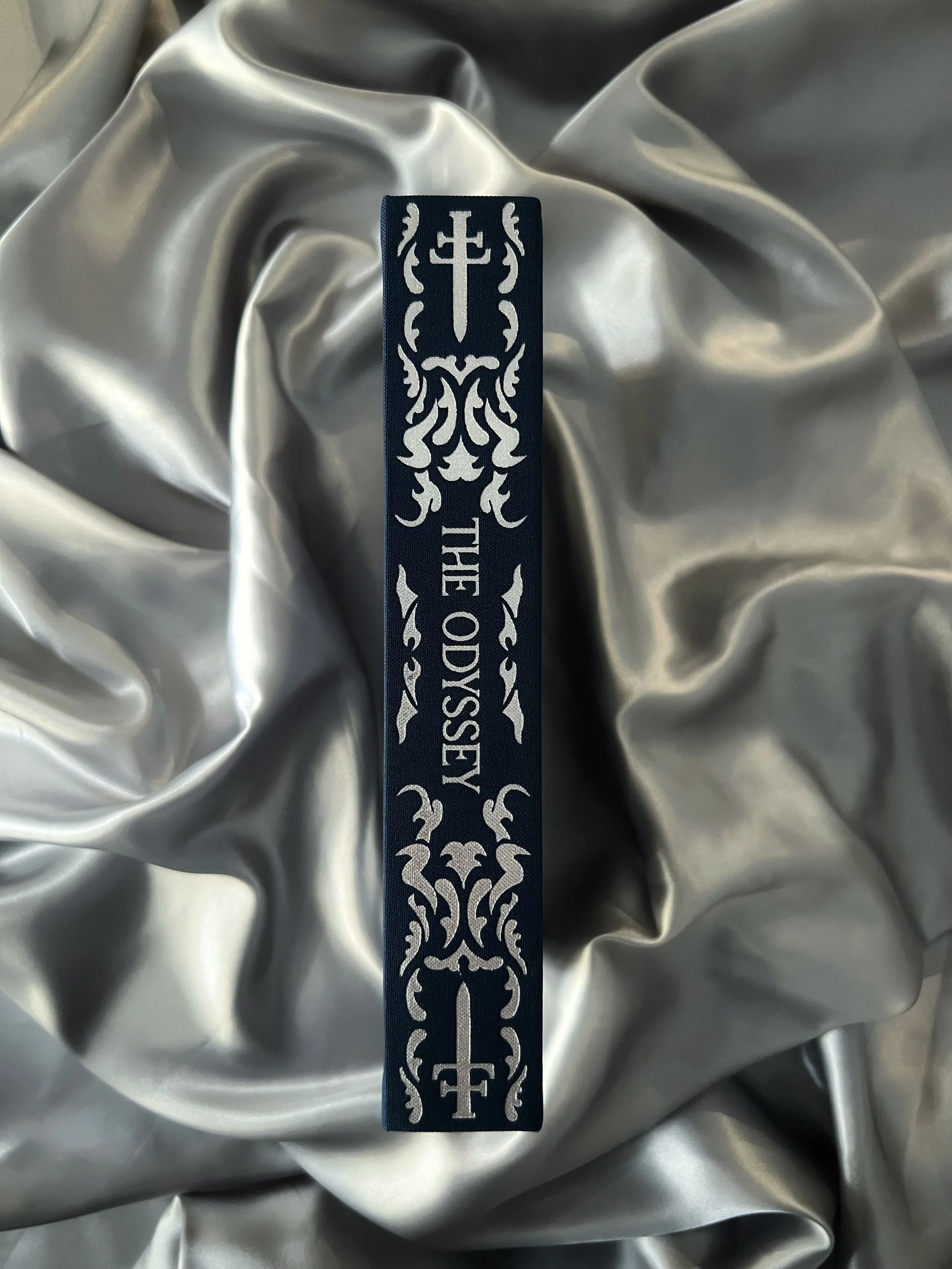 Close-up of The Odyssey collector’s edition spine with navy linen binding and silver foil embellishment.