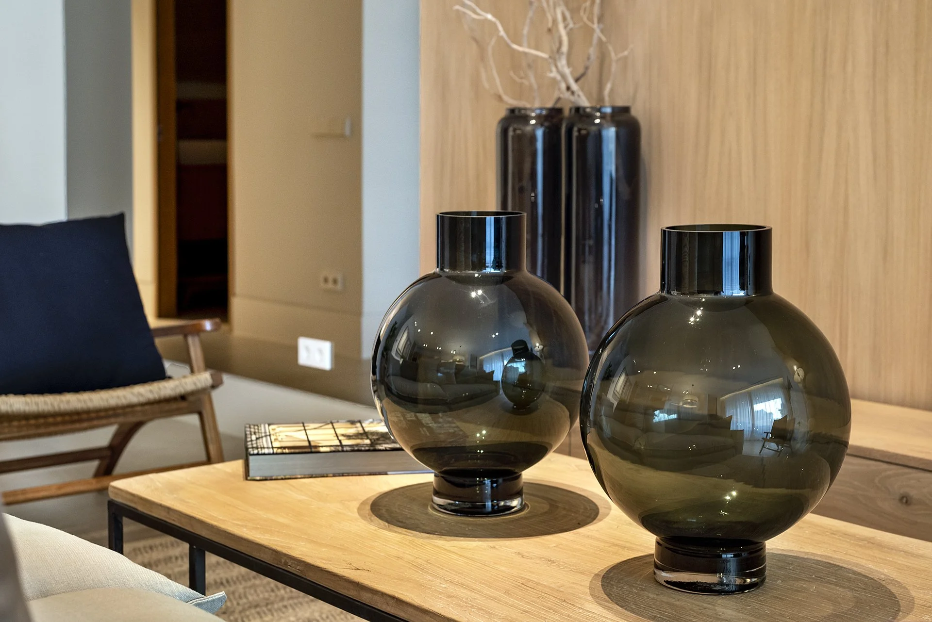 Decorative black glass vases on a wooden table in a modern living room