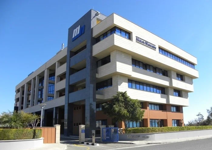 Modern multi-story office building with the Microsoft logo and department sign, featuring large windows and a landscaped exterior.