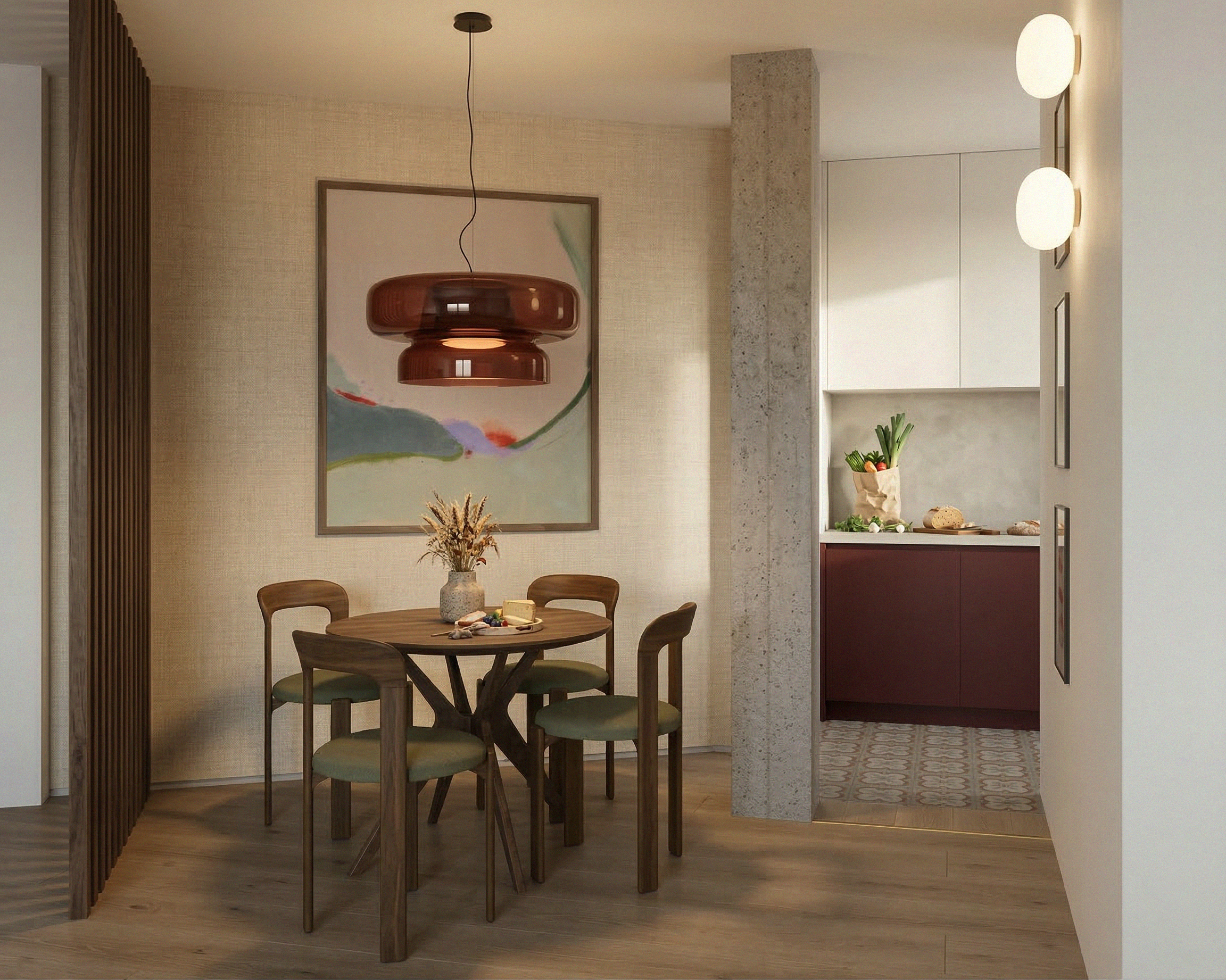 Vista interior de una sala que muestra una mesa de madera con siete sillas, decorada con un jarrón con flores secas y una bandeja con frutas y pan. Al fondo, un cuadro abstracto, una columna de piedra y un área de kitchenette con gabinetes blancos y plantas.