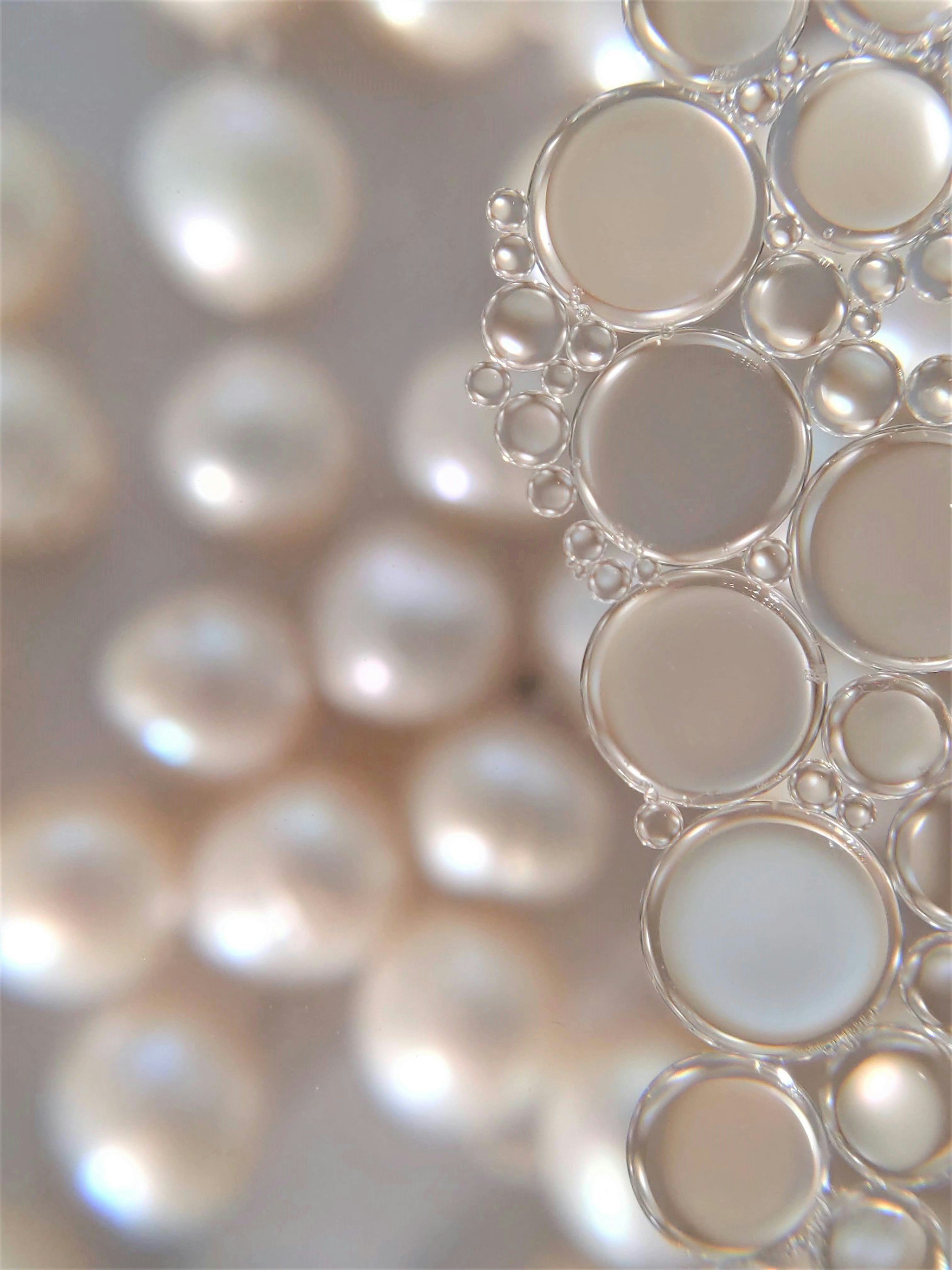 Close-up of bubbles in a liquid, showing different sizes and transparent surfaces with a light background.