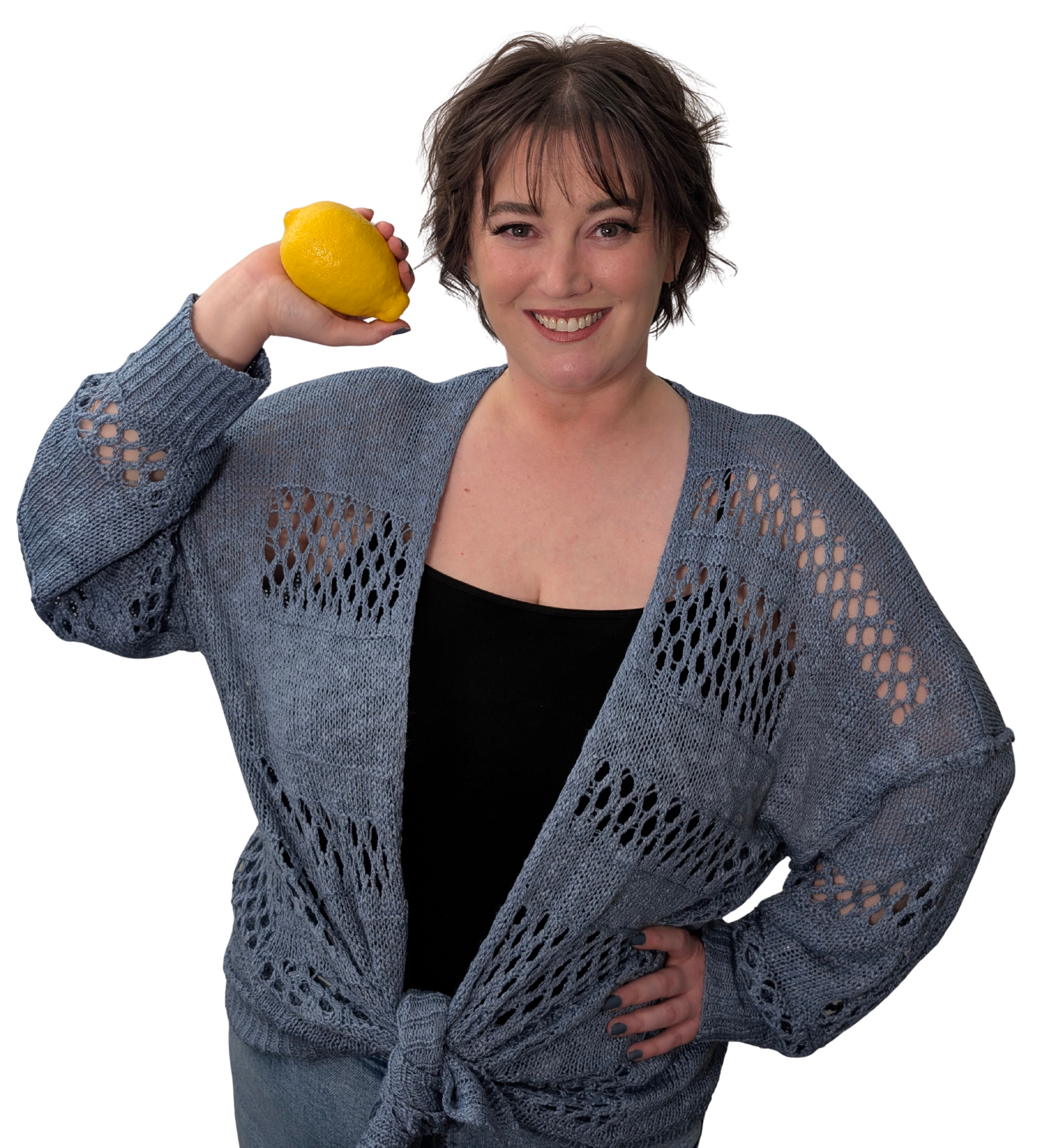 A woman with short, wavy brown hair smiling and holding a yellow lemon beside her head.