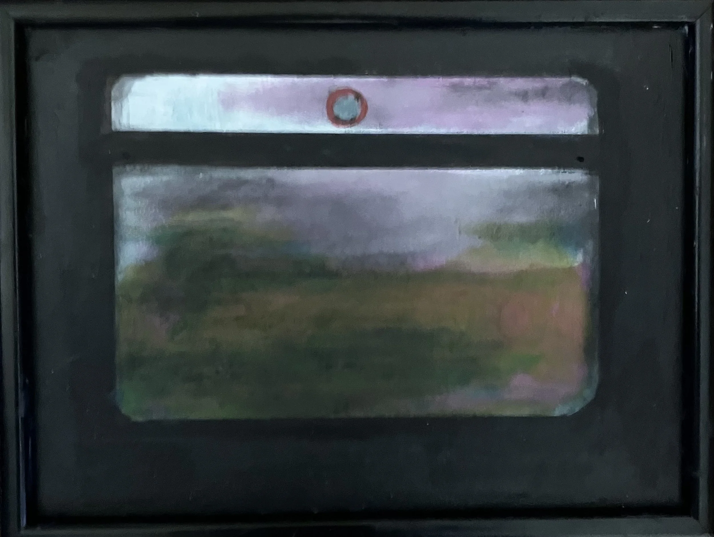 A black mailbox with a reflective surface showing a blurry landscape of trees and sky.