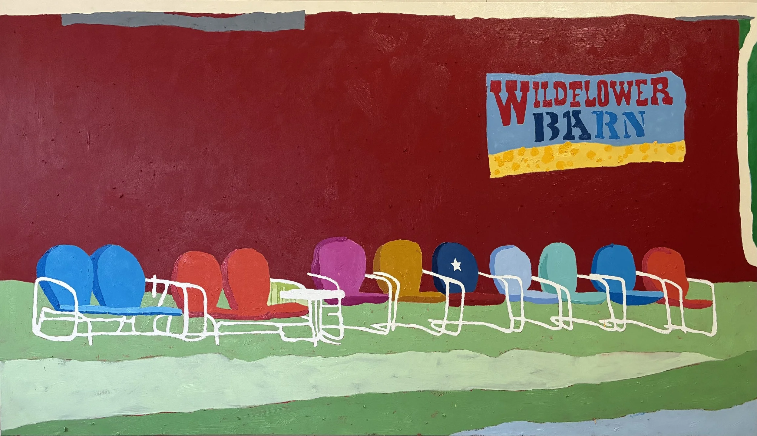 Colorful row of vintage lawn chairs in front of a red wall with a sign that reads 'Wildflower Barn'