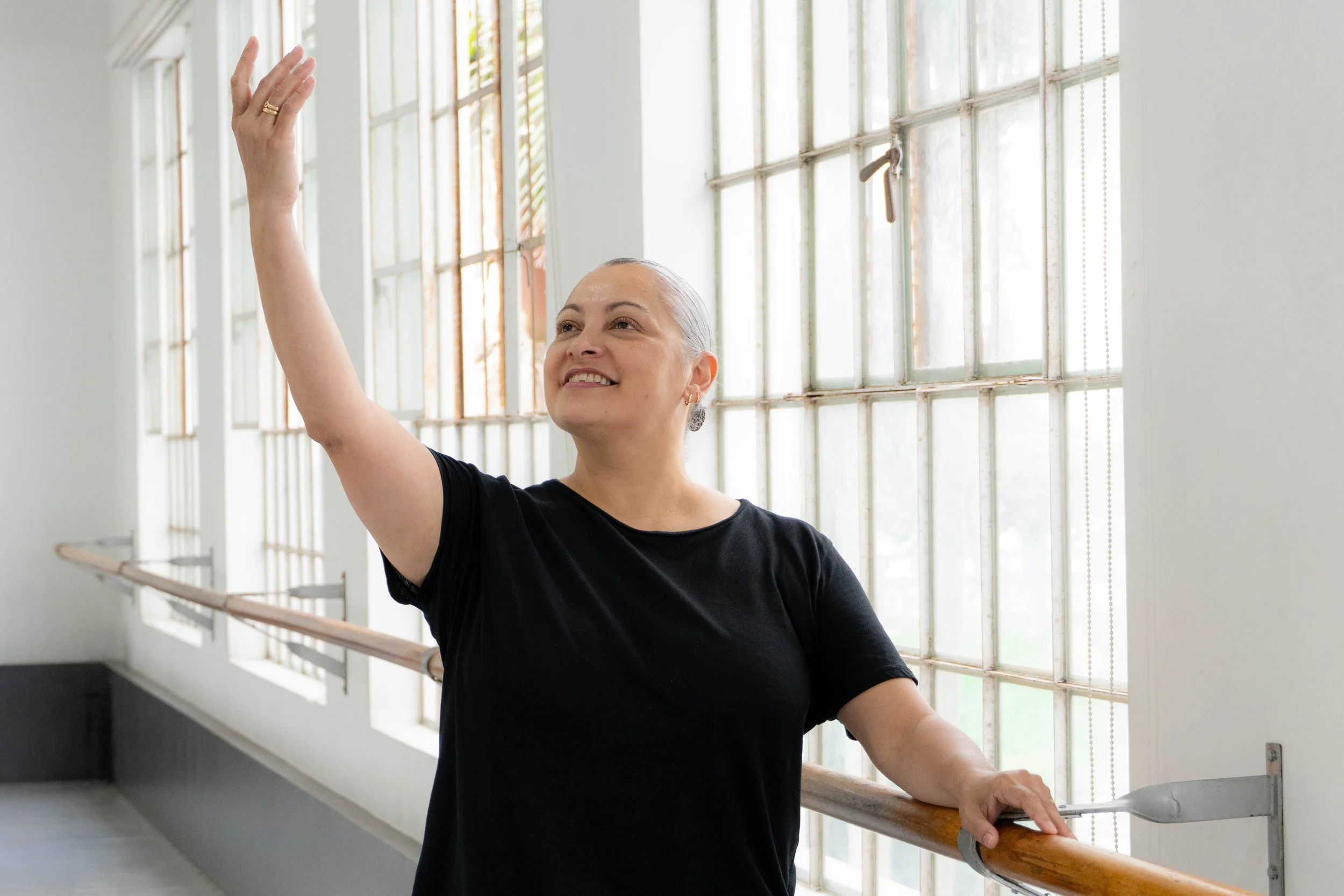 Mujer bailando en una clase de ballet en un estudio con ventanas grandes