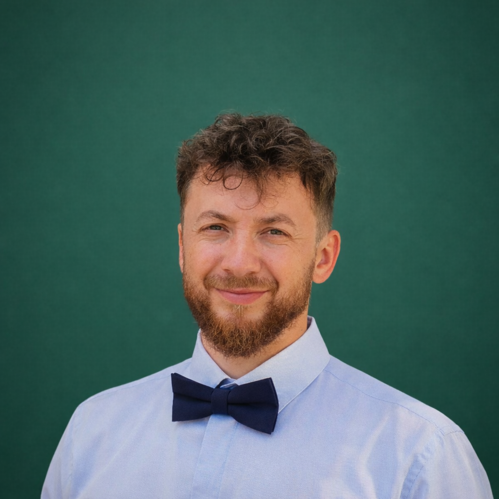Headshot of smiling female tutor with long curly brown hair wearing a lanyard.