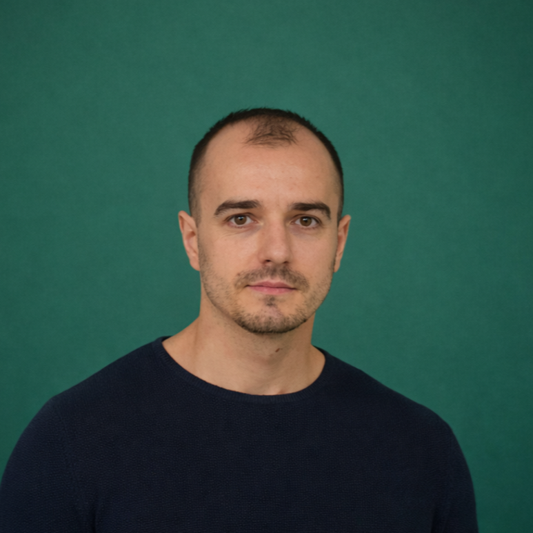 Headshot of smiling male tutor with medium-length black hair wearing a lanyard.