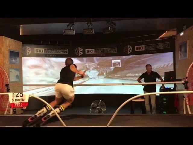 Person on a SkyTech Ski Simulator with a screen and coach in front.