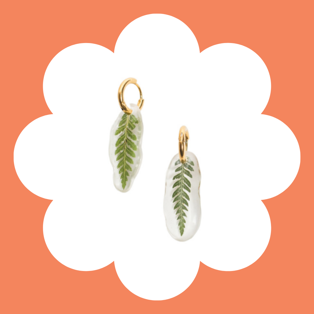 Solarized leaf earrings with gold hooks on a white background with a peach-colored border.
