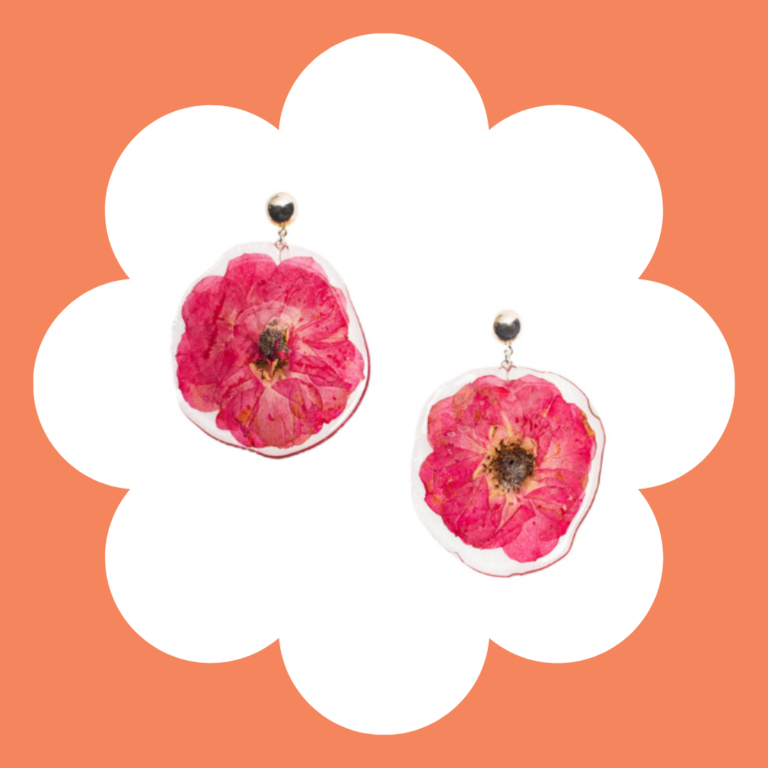 Pair of earrings with dried pink flowers on a white and orange background.