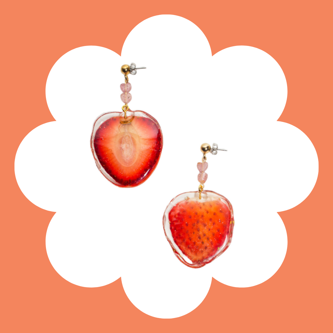 Earrings with strawberry-shaped pendants on a floral background.