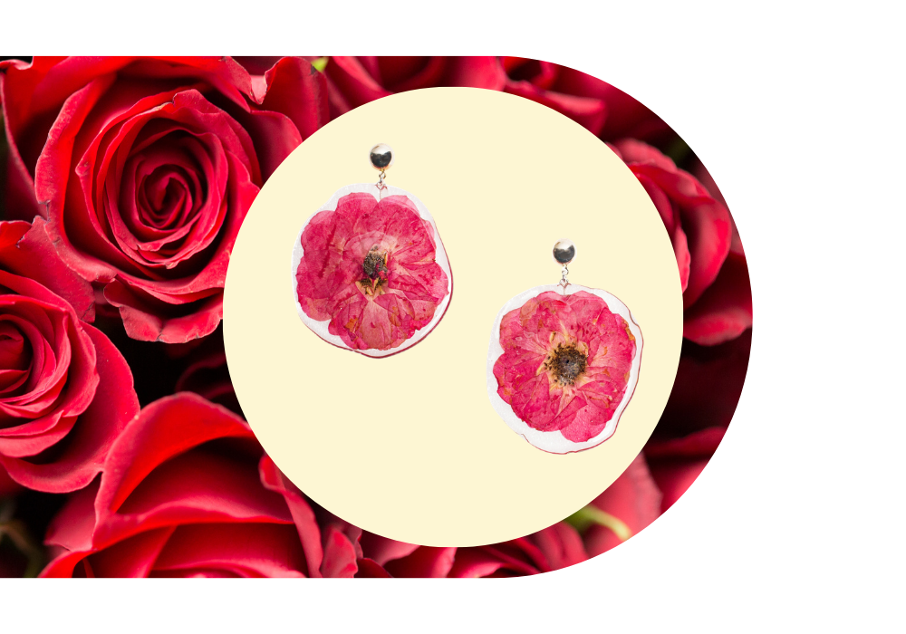 Pink flower earrings with dried rose petals on a background of red roses.