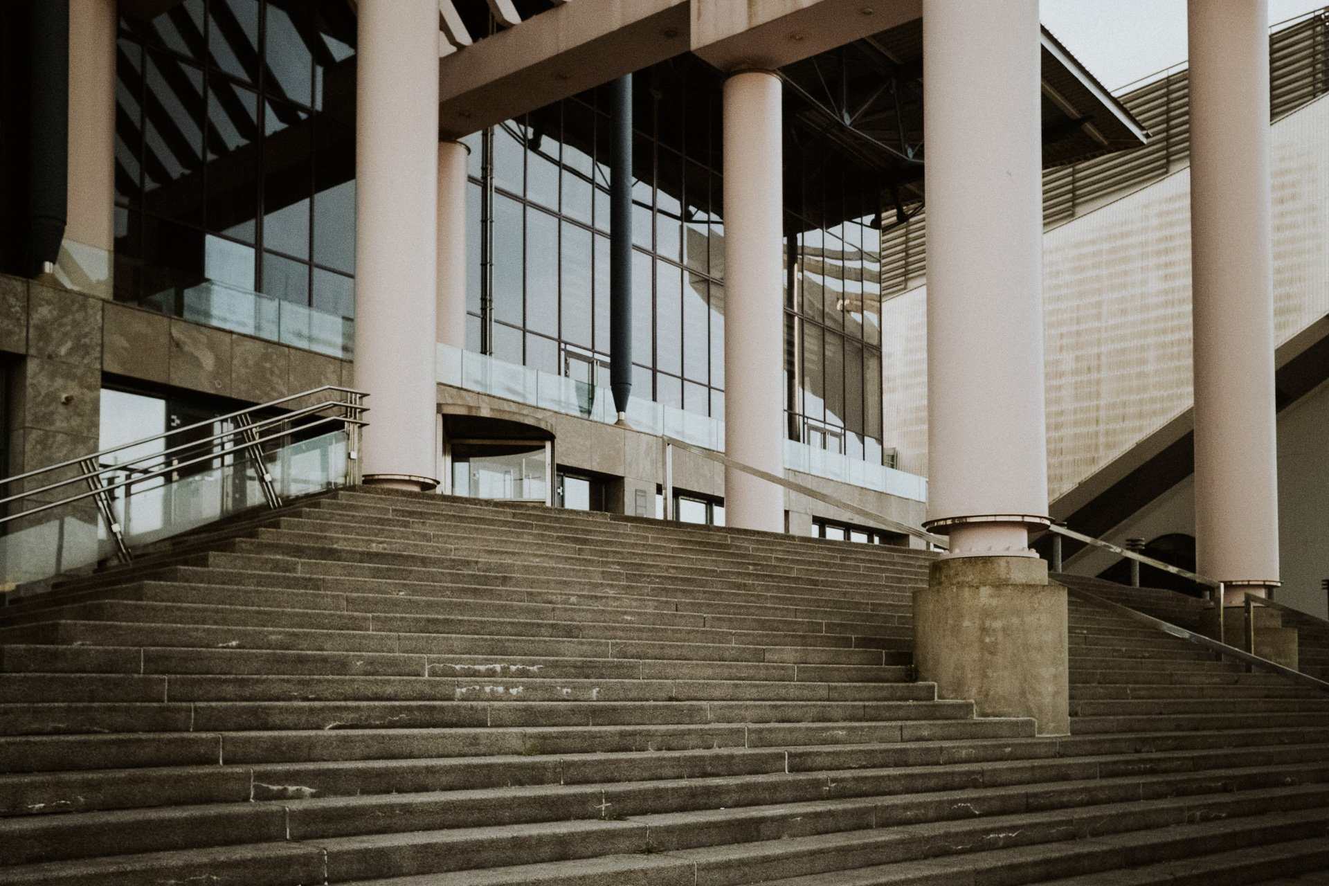 Breite Steintreppe vor einem modernen Gebäude, mit klarer Linienführung nach oben.