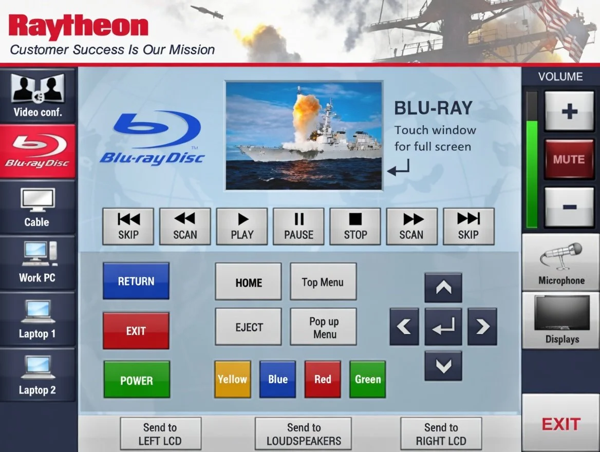 A control panel for a Blu-ray player or television with various buttons for media control, including options for video conferencing, Blu-ray disc, cable, PC, laptop, volume control, and color buttons, along with a picture of a warship launching a missile.