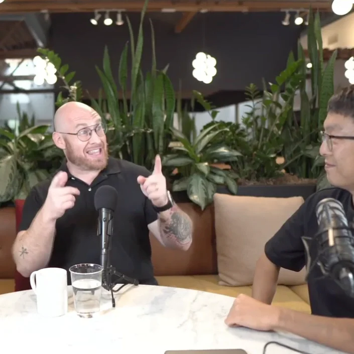Jeff Strauss gesturing excitedly while explaining something to a podcast host. Both men are in front of microphones.