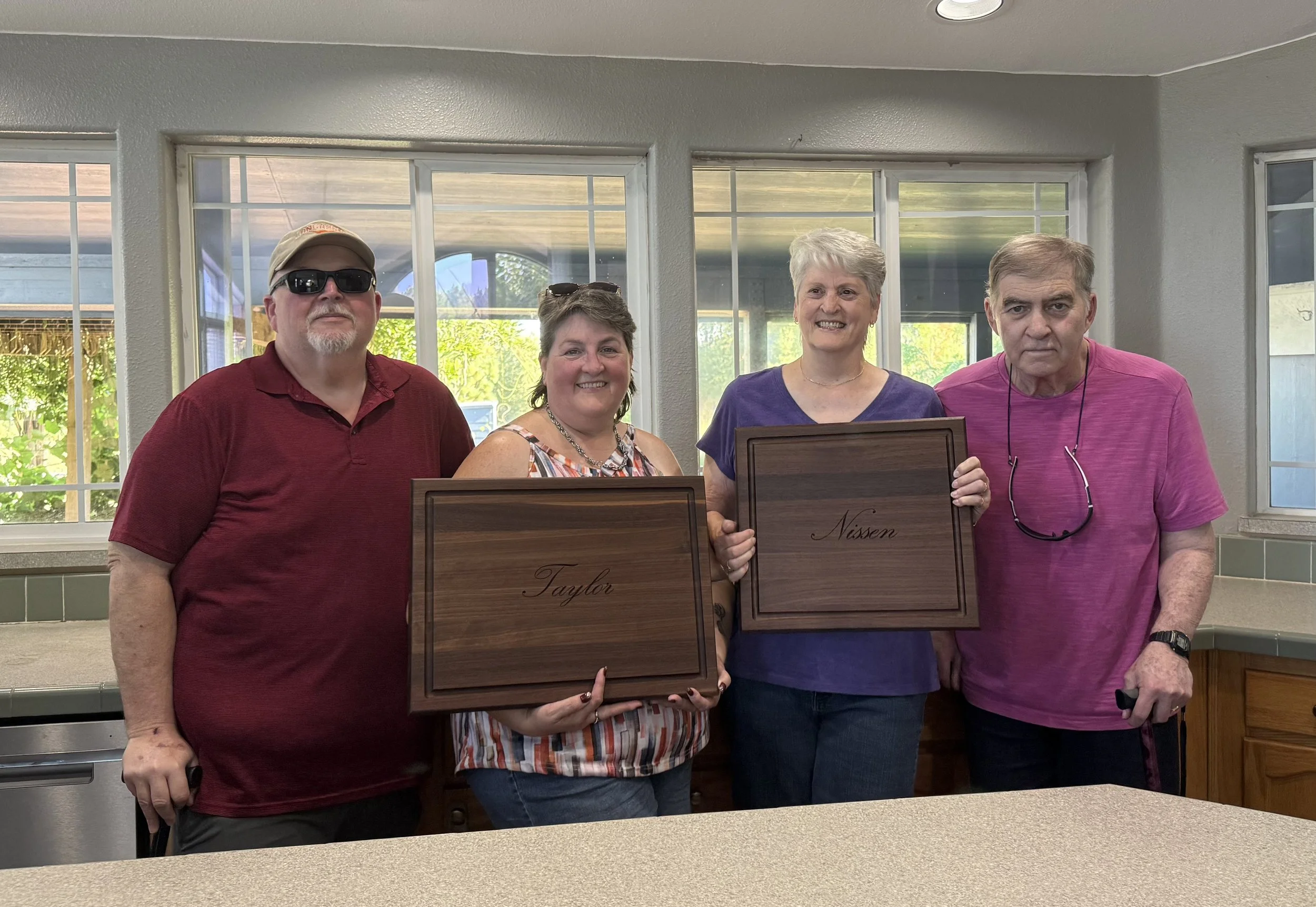 Four people standing inside a room holding handcrafted wooden plaques.