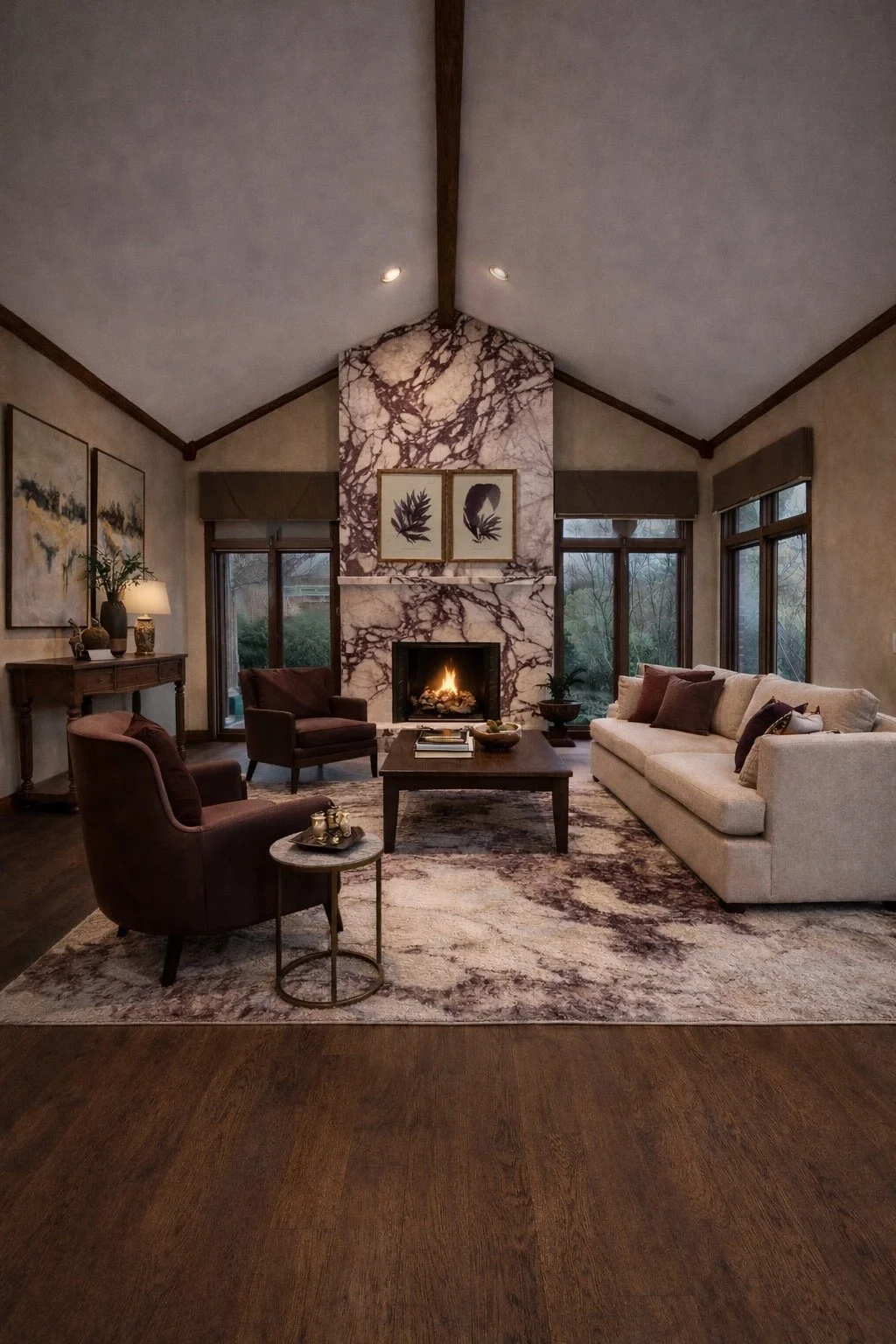 Living room with a fireplace, beige sofa, and armchairs, a wooden coffee table, artwork, and large windows.