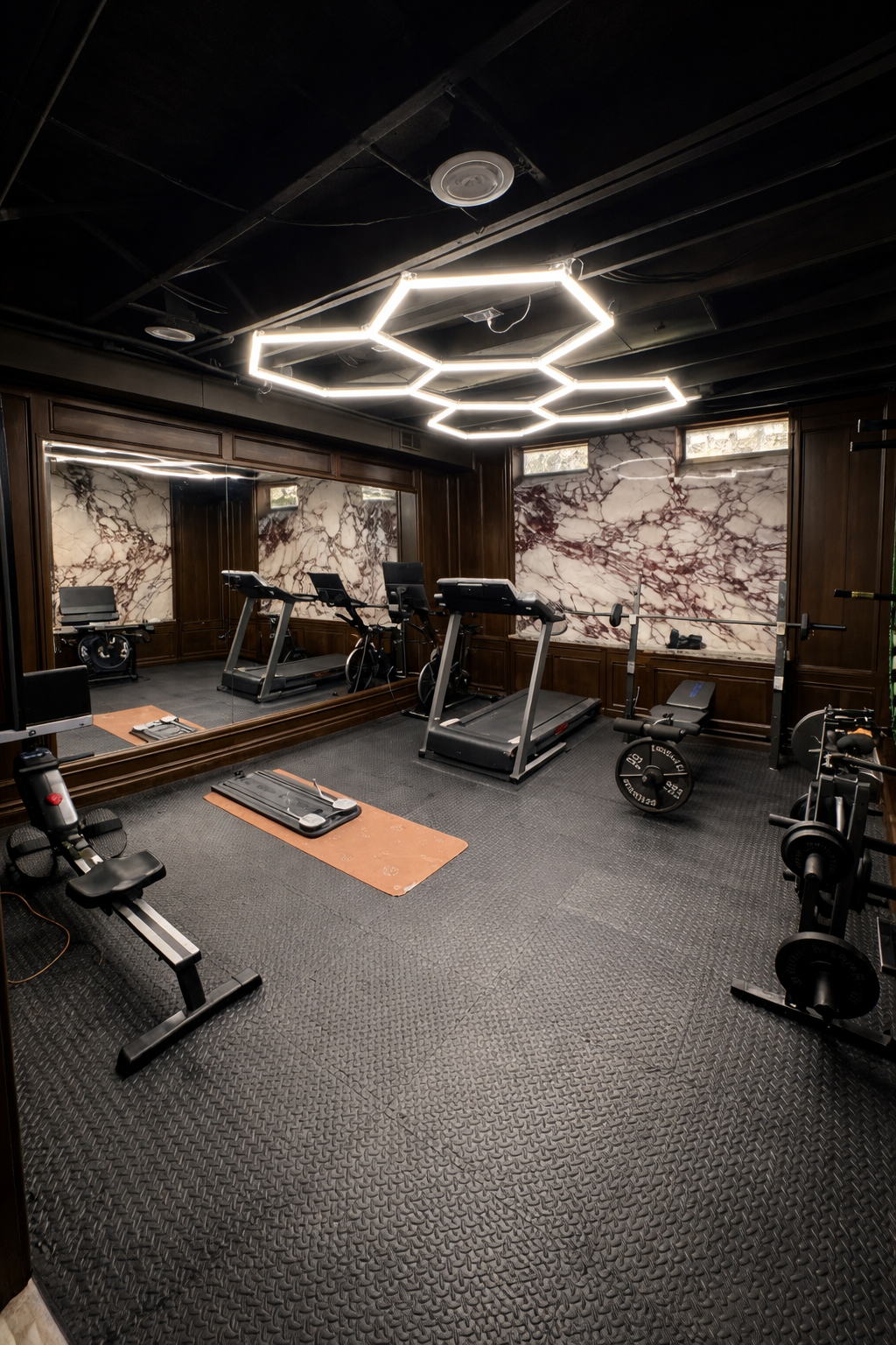 Home gym with treadmill, elliptical, weightlifting equipment, large mirror, marble walls, and modern hexagonal ceiling lights.