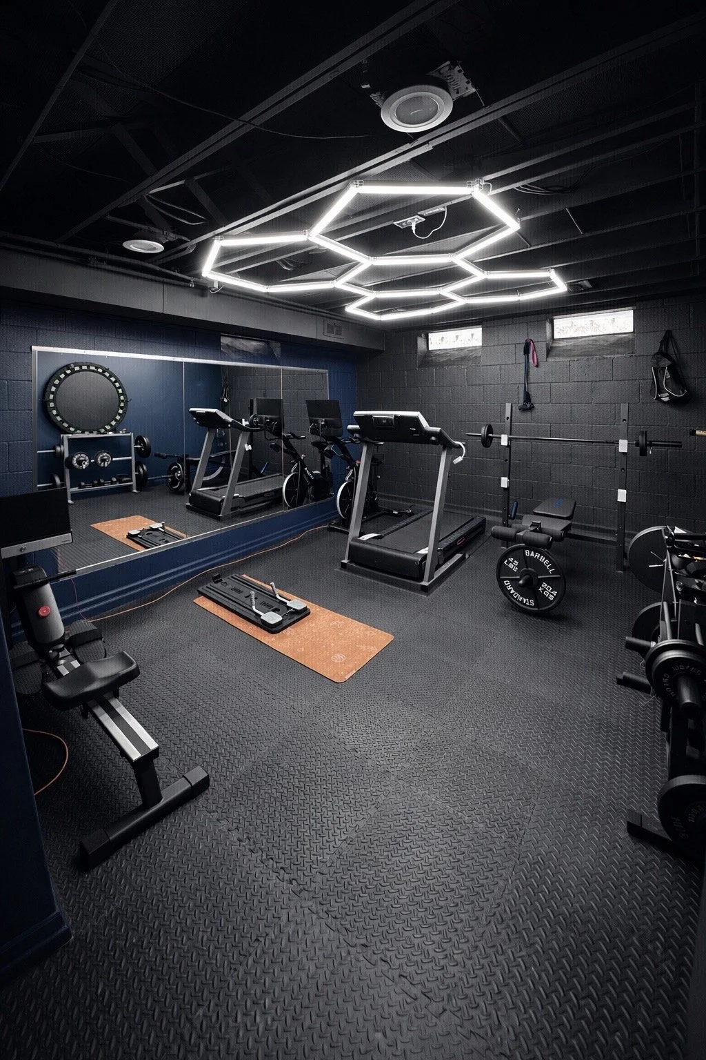 Indoor gym with treadmills, weightlifting equipment, mirror wall, and hexagonal LED ceiling lights.