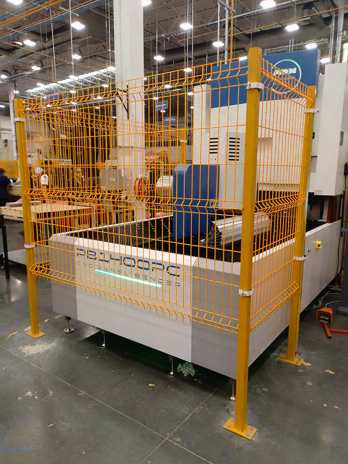 Manufacturing robot enclosed in yellow safety fencing in an industrial facility