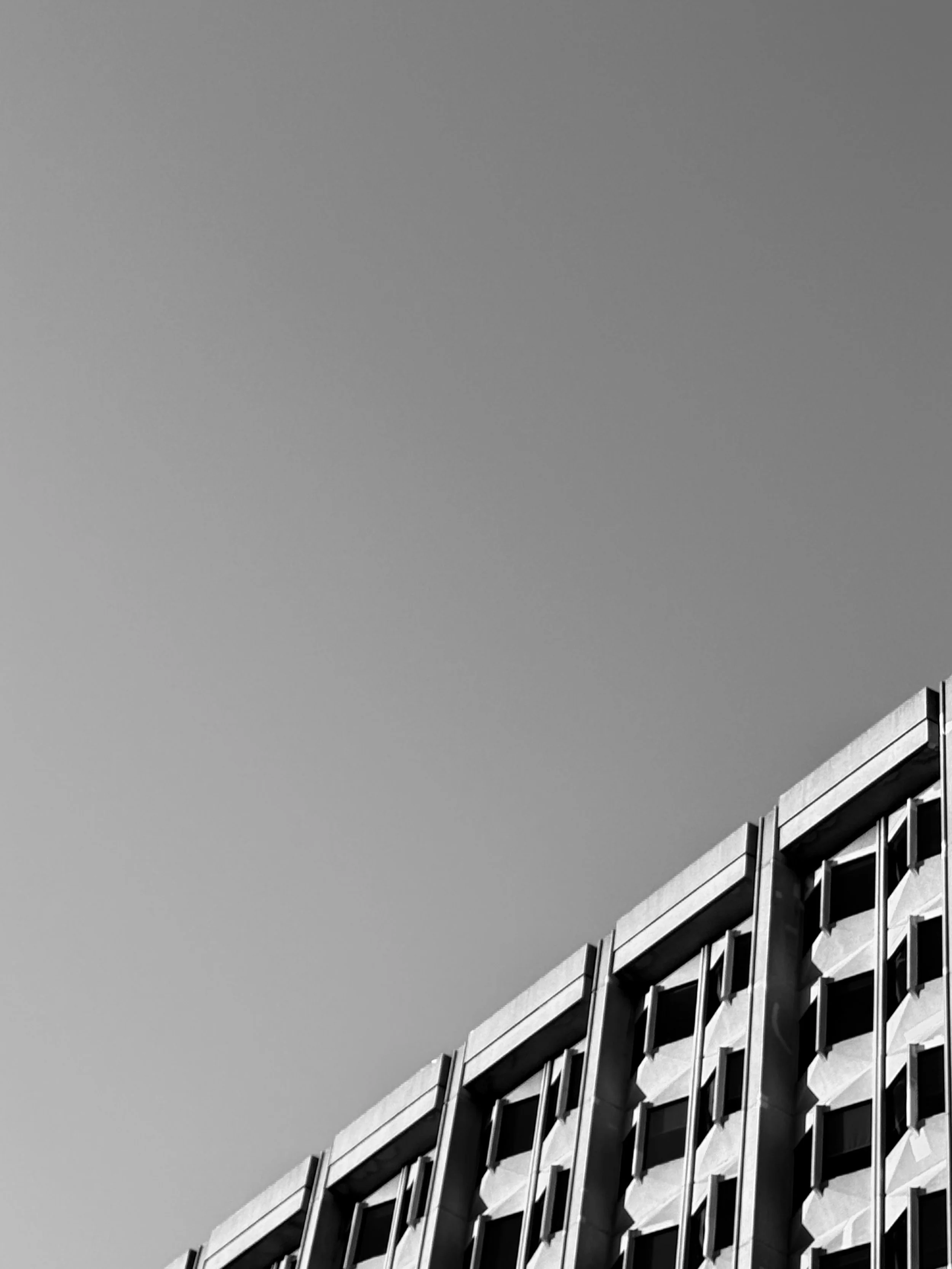Close-up view of a modern building with geometric patterns on its facade, set against a clear sky.
