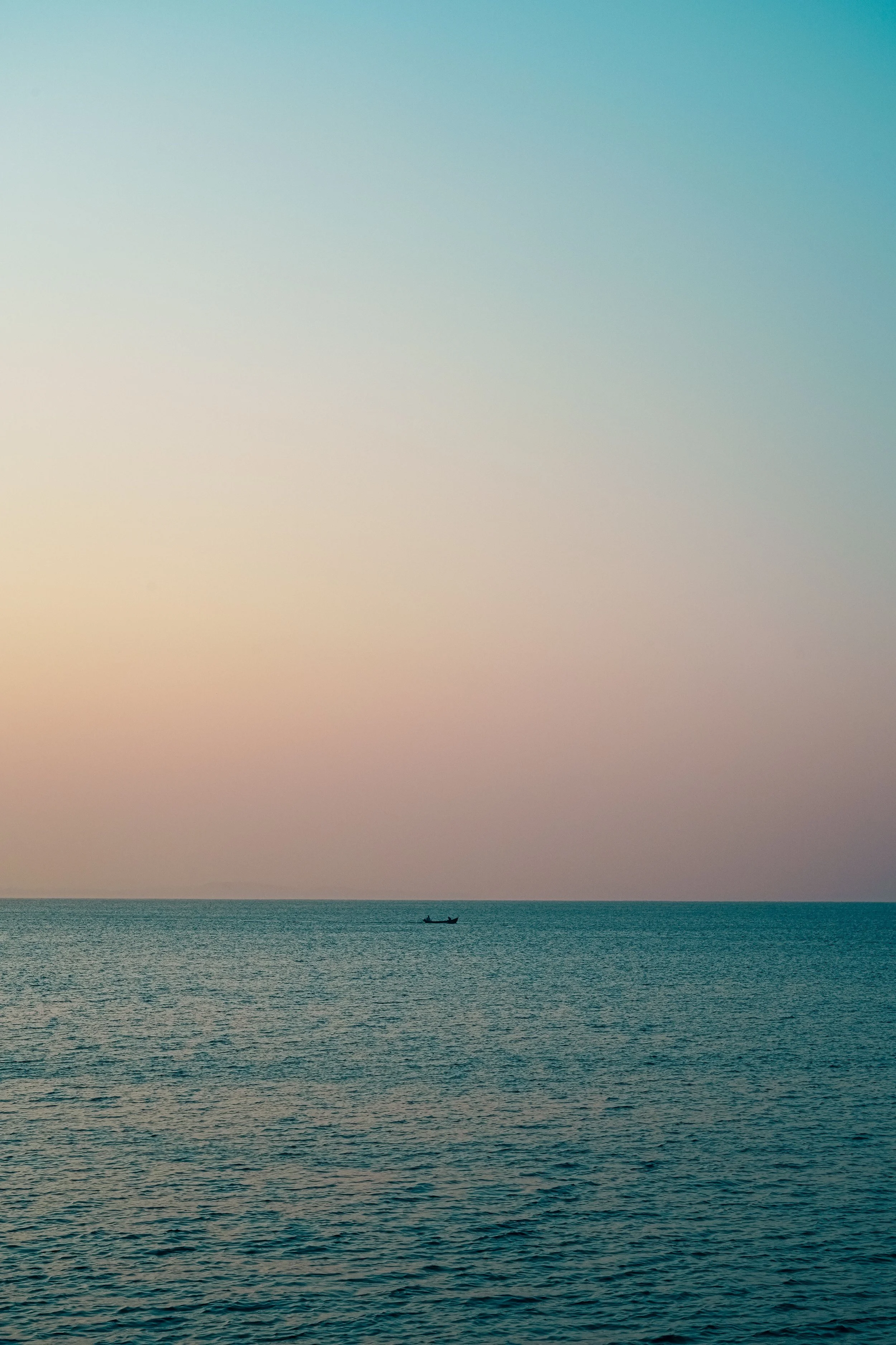 A boat floating on calm ocean waters under a pastel-colored sky with shades of teal, pink, and yellow.