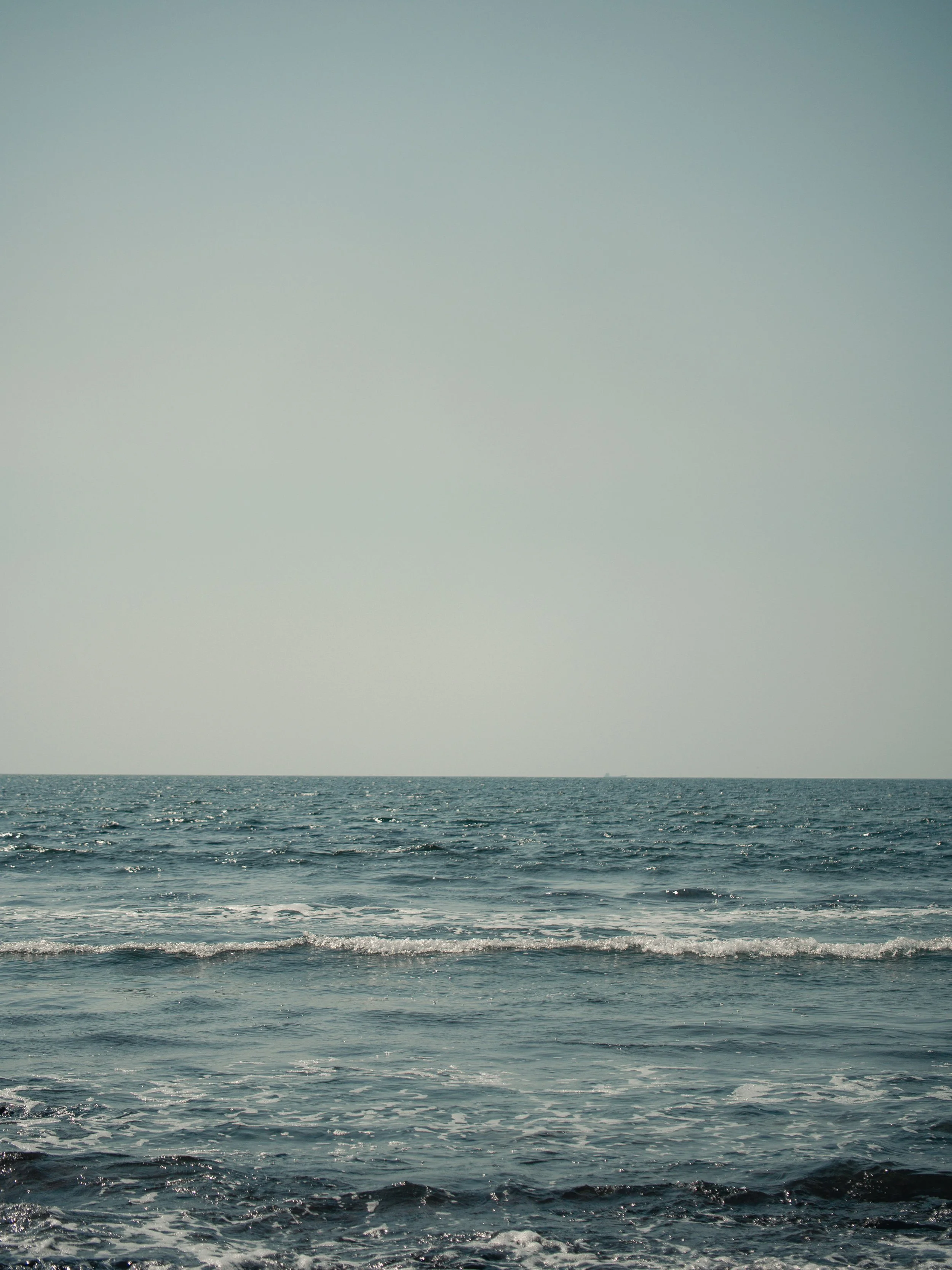 View of the ocean with waves, under a clear sky.