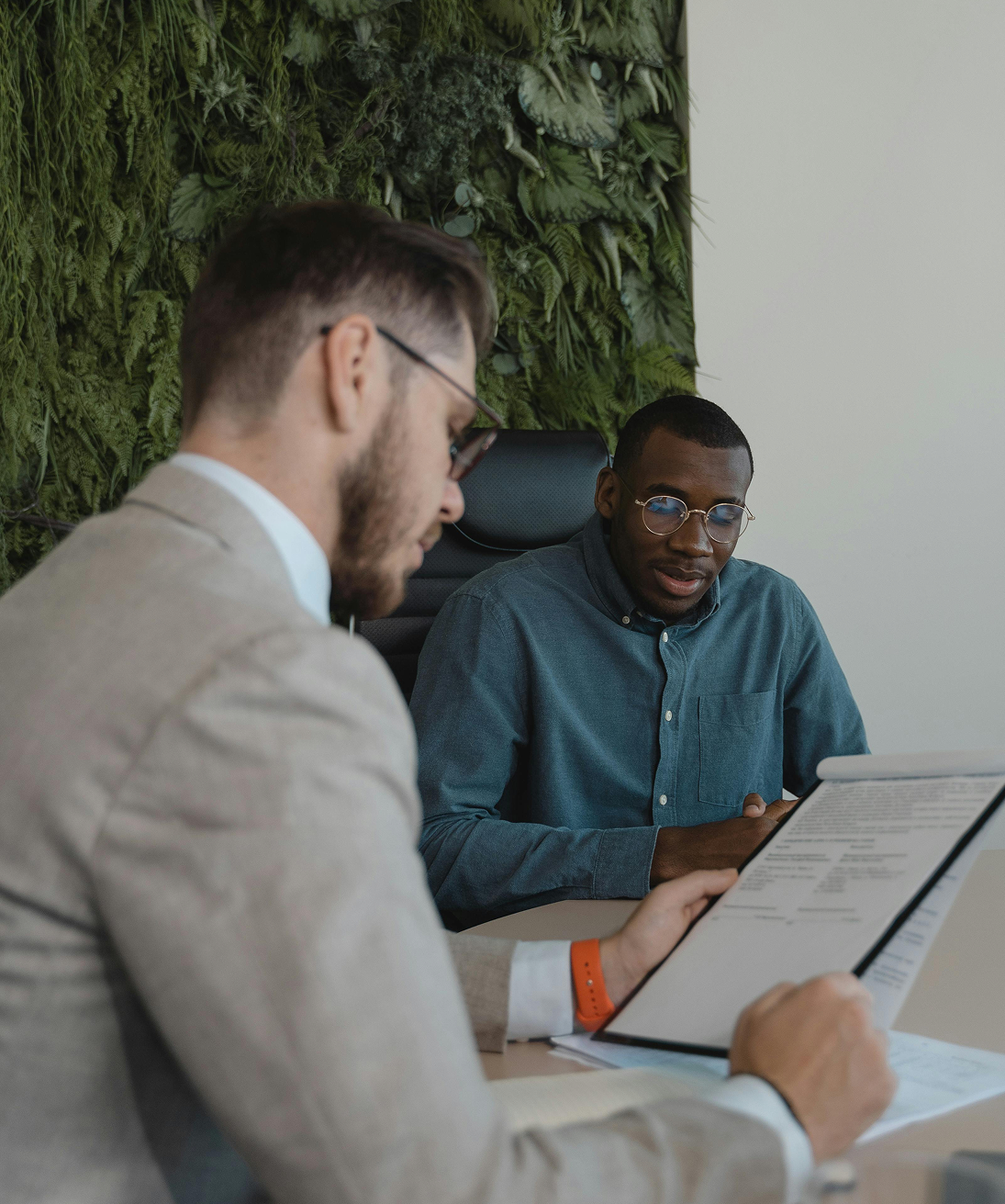Two professionals sitting at a desk reviewing a document together in a modern office.