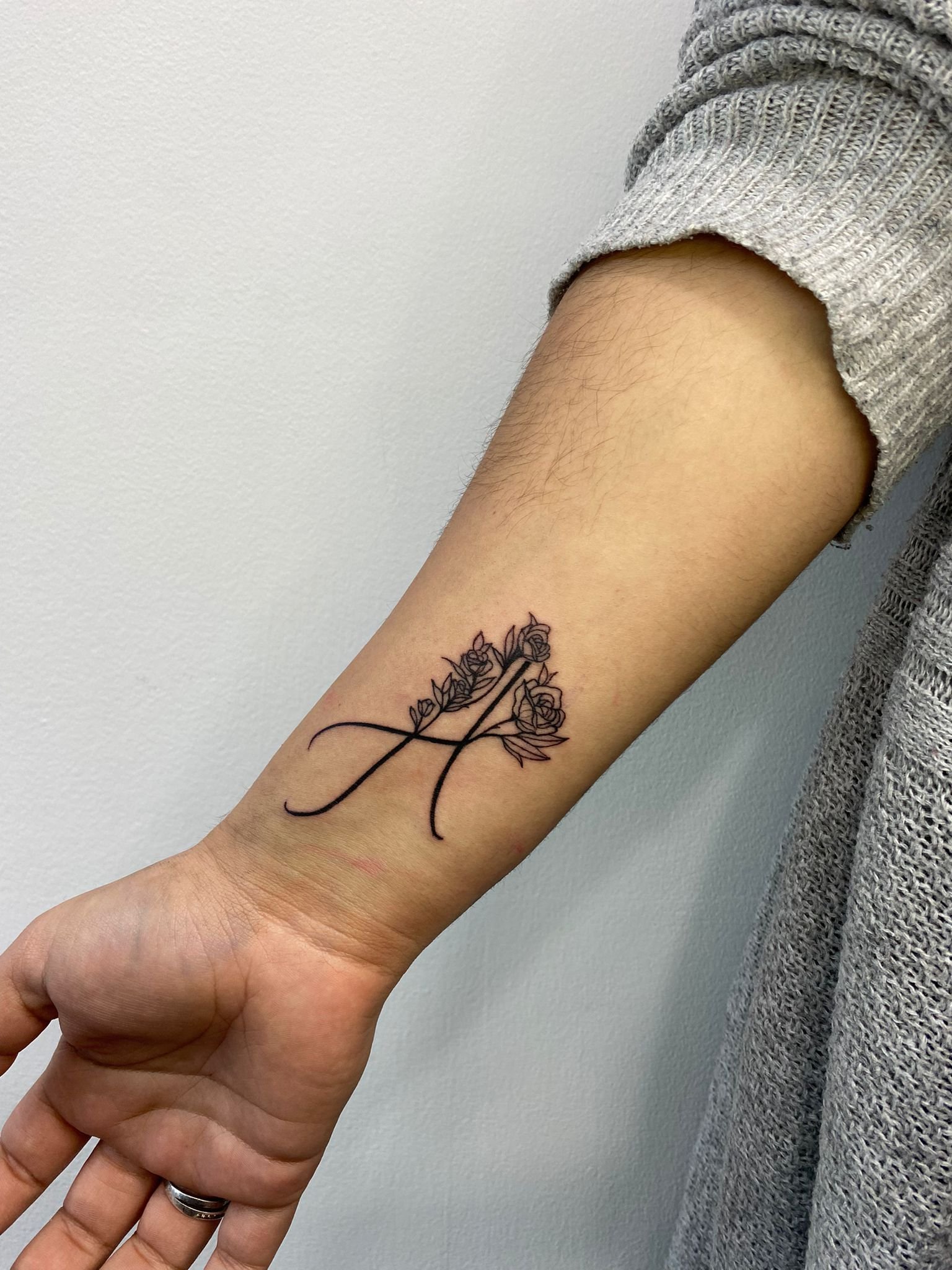 Tatuagem de um ramo com rosas na parte interna do antebraço