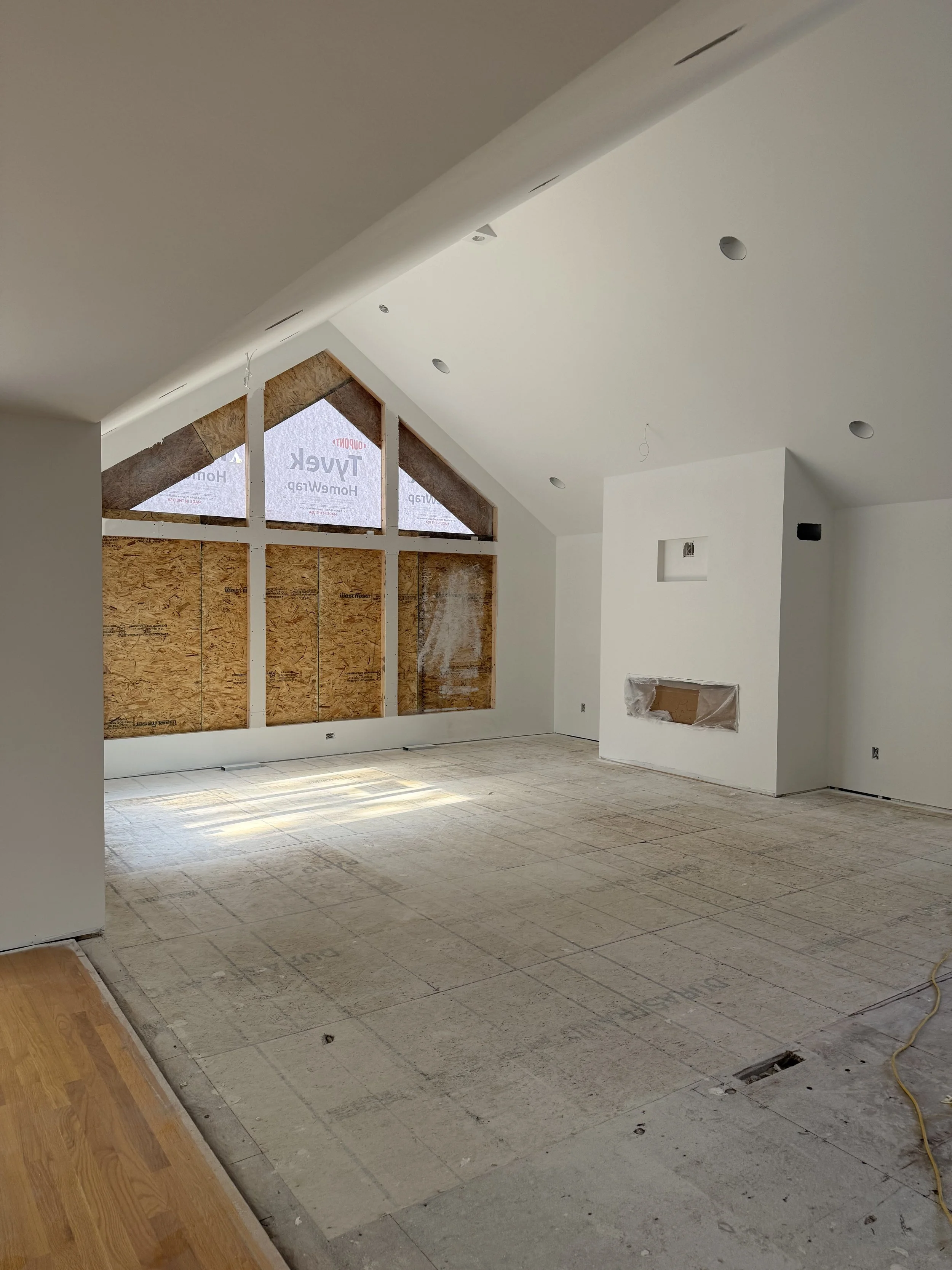Custom home interior under construction by Sprengeler Construction featuring vaulted ceiling, large window framing, and open-concept layout in progress