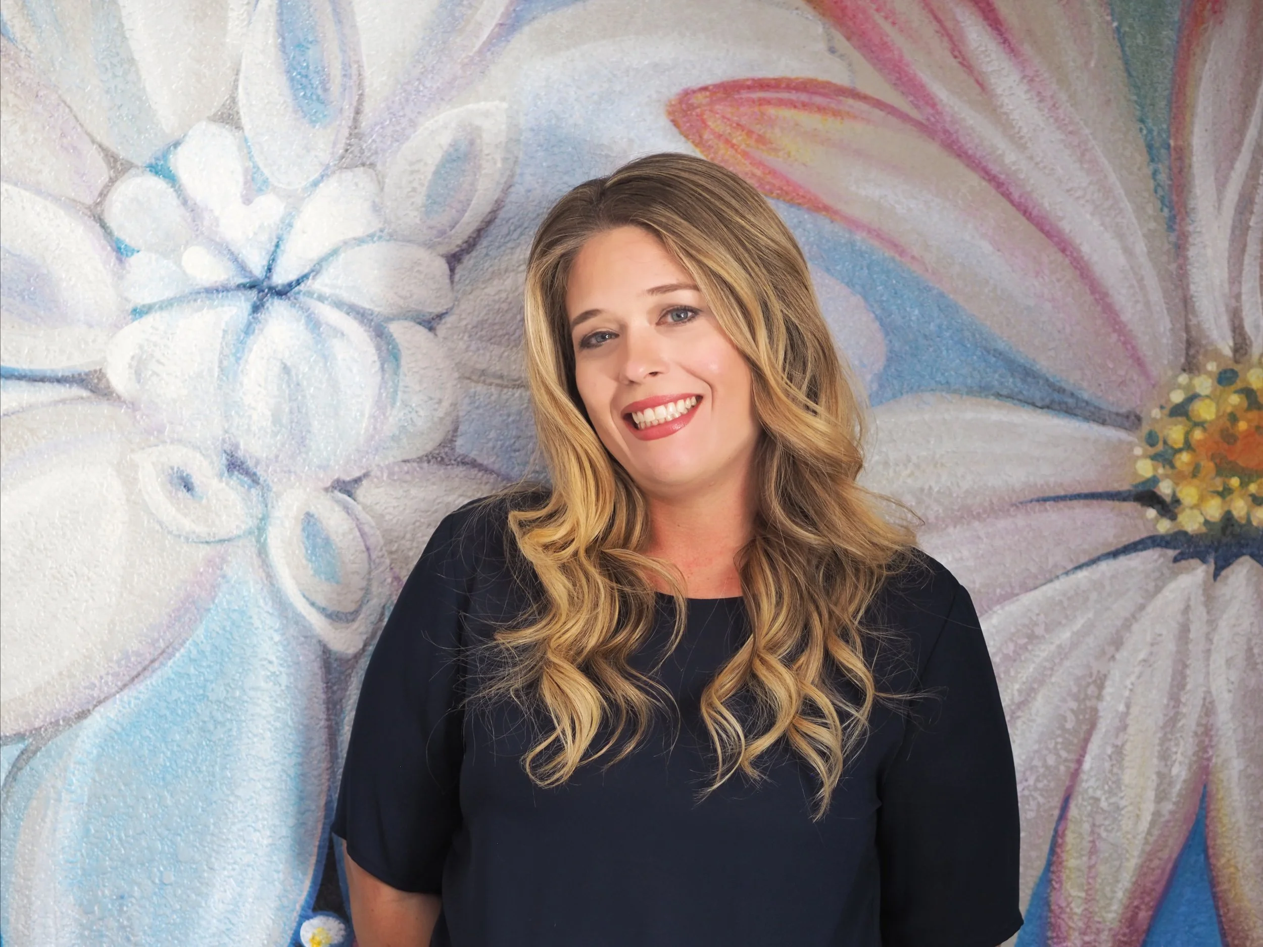 Therapist smiling standing in front of mural