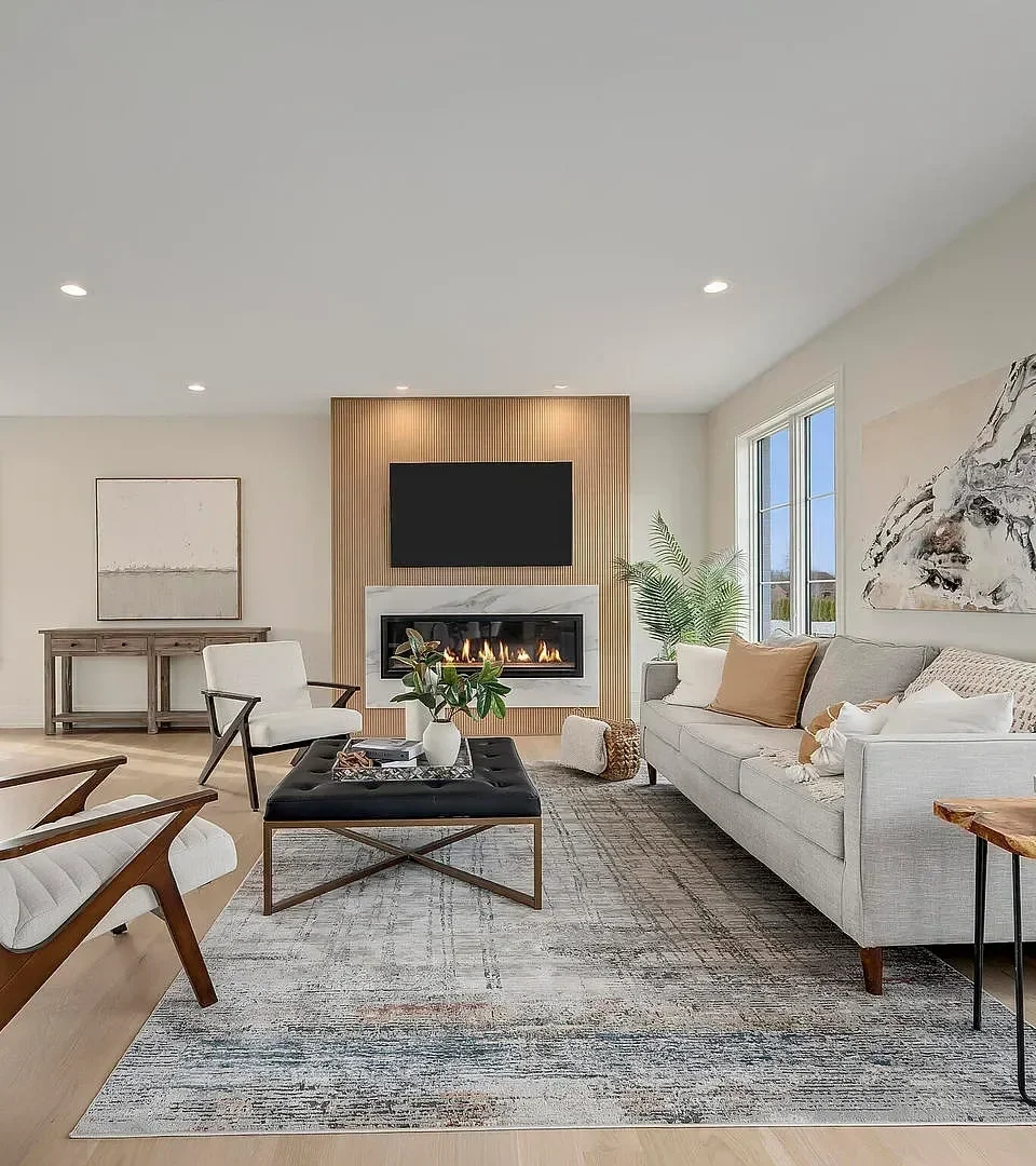 Living room with a sofa, armchair, coffee table, fireplace, tv, large plant, artwork, and windows.