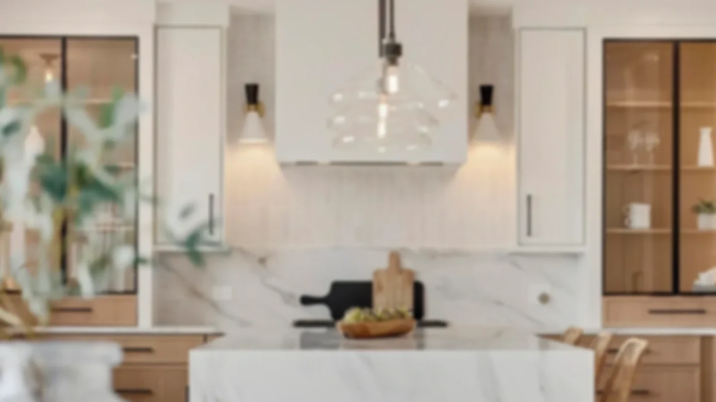 Modern kitchen with white cabinetry, a marble island, and wooden accents, including glass-front cabinets and a chandelier over the island.