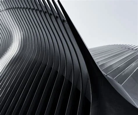 Close-up view of modern architectural building featuring black vertical fins and silver curved panels.