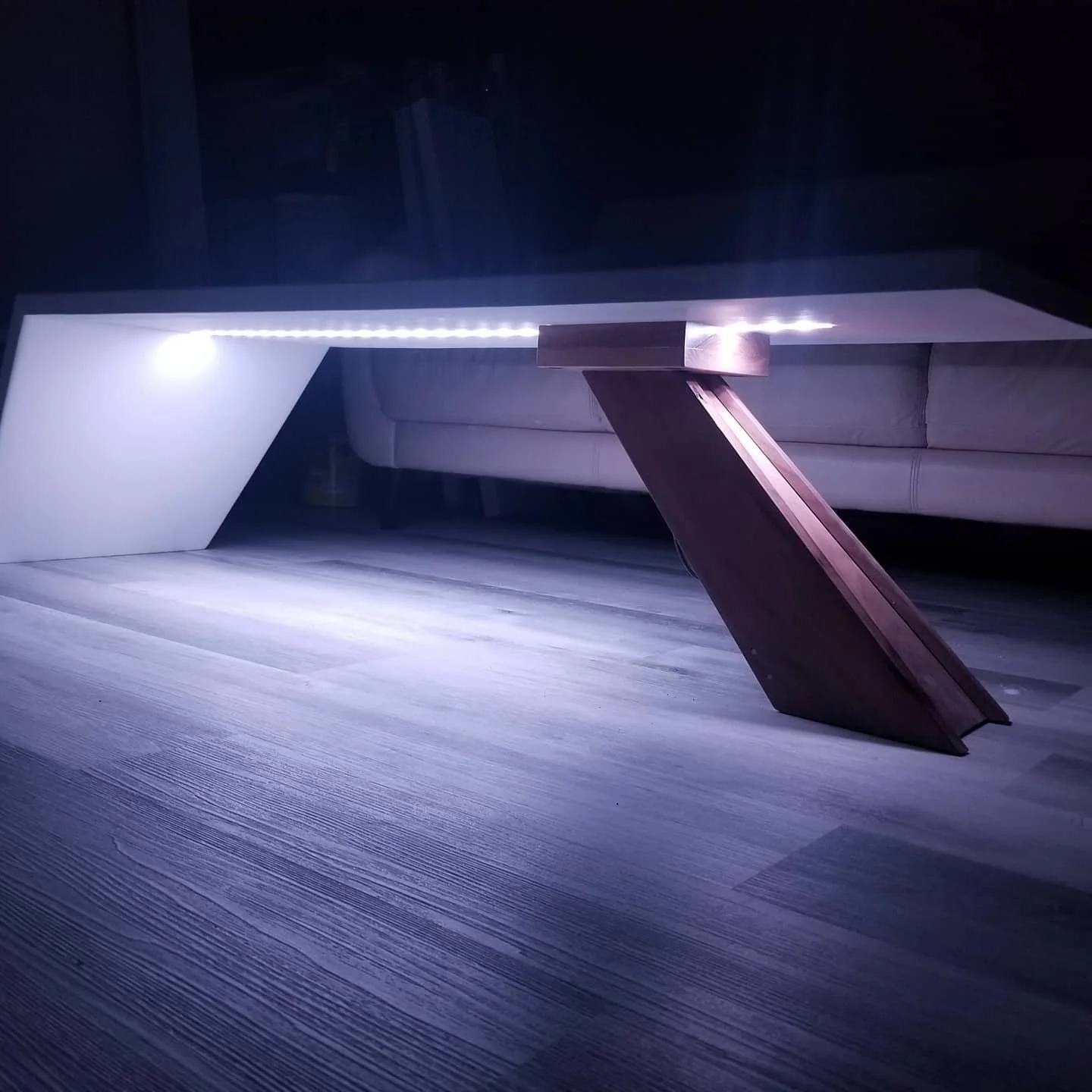 Custom coffee table.  1 piece concrete L with a single, Diagonal, Walnut Leg and inset smart, L.E.D light strip.